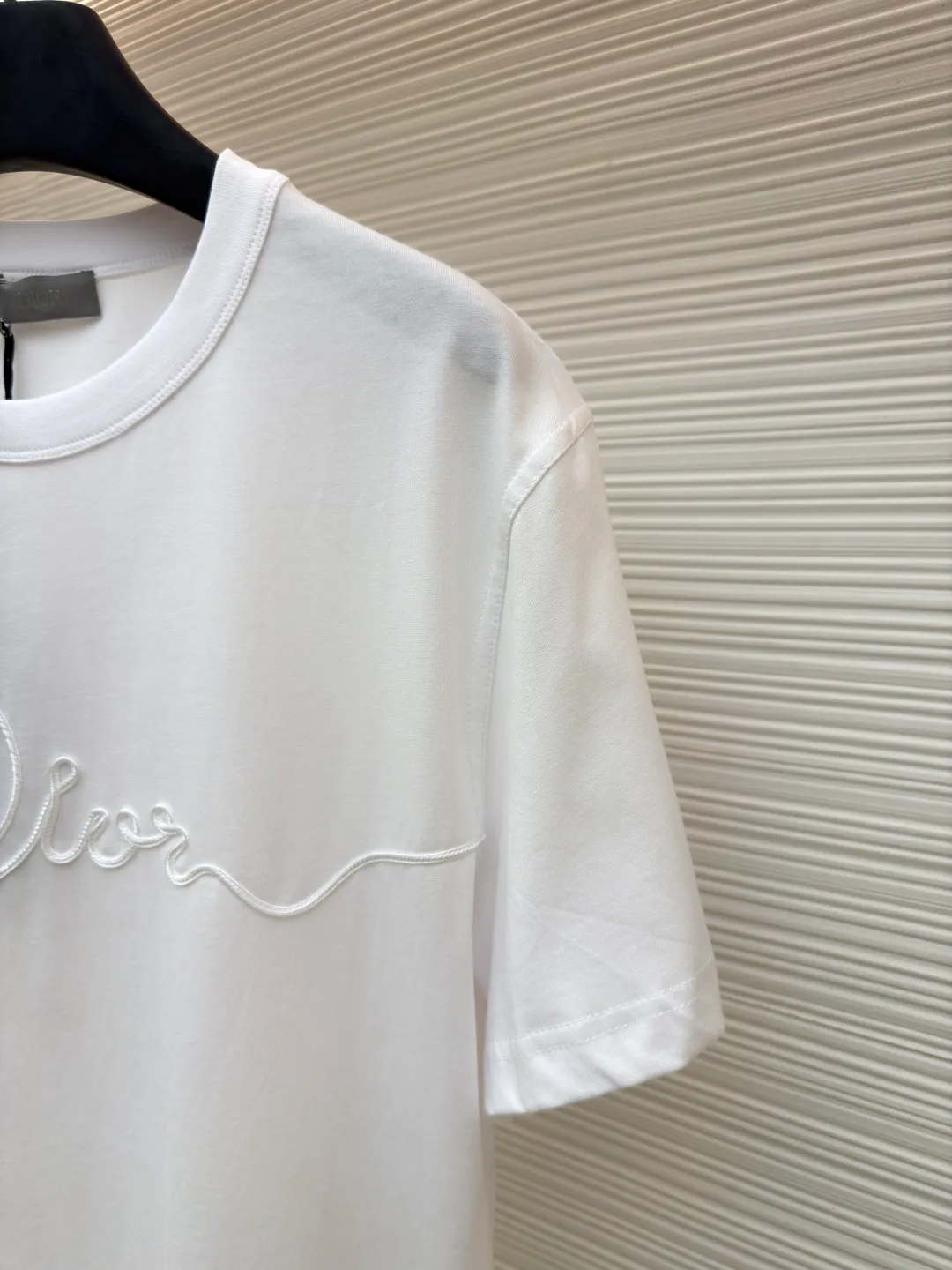 Dior satin emblem round neck short sleeves ●Original version: purchased and developed by 7089 ●Item number: 1681695-A00 ●Fabric: cotton jersey fabric ●Technology: embroidery production ●Color: white ●Version: fitted version ●Weight: about 205 grams ●Size: XS-S-M-L ●Description: The main body is made of 24-count special-spun compact cotton. The weight of 185g/㎡ is light to medium, ensuring the lightness, breathability and good drape of the T-shirt. It is suitable for both spring wear alone and as an inner layer. With 32 pieces of 1×1 rib, 300g/㎡. Its special spinning and compacting process means that compact spinning technology is used in the spinning process, which effectively reduces the hairiness of the yarn, making the yarn smoother and stronger. The woven fabric therefore has the advantages of compact structure, smooth surface, and resistance to pilling. The final dark gray tone is combined with the simple texture of jersey to create a high-end matte texture. Embroidery decoration in the form of satin ribbons, which are fixed on the fabric through special processing. The texture brought by this process is usually different from the woven texture and slight luster of the main knitted fabric. It forms a delicate and accessible visual and tactile focus on the matte dark gray base, enhancing the craftsmanship, design and uniqueness of the single product. The overall wiring is straight and delicate, the fabric is comfortable and soft, and the color is consistent without color difference. It can be matched with the same style to create a fashionable look and control various occasions. Customized accessories, complete with three standards, same style for men and women!