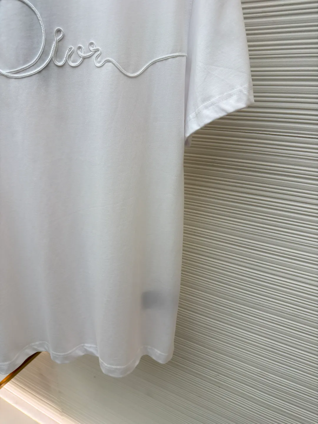 Dior satin emblem round neck short sleeves ●Original version: purchased and developed by 7089 ●Item number: 1681695-A00 ●Fabric: cotton jersey fabric ●Technology: embroidery production ●Color: white ●Version: fitted version ●Weight: about 205 grams ●Size: XS-S-M-L ●Description: The main body is made of 24-count special-spun compact cotton. The weight of 185g/㎡ is light to medium, ensuring the lightness, breathability and good drape of the T-shirt. It is suitable for both spring wear alone and as an inner layer. With 32 pieces of 1×1 rib, 300g/㎡. Its special spinning and compacting process means that compact spinning technology is used in the spinning process, which effectively reduces the hairiness of the yarn, making the yarn smoother and stronger. The woven fabric therefore has the advantages of compact structure, smooth surface, and resistance to pilling. The final dark gray tone is combined with the simple texture of jersey to create a high-end matte texture. Embroidery decoration in the form of satin ribbons, which are fixed on the fabric through special processing. The texture brought by this process is usually different from the woven texture and slight luster of the main knitted fabric. It forms a delicate and accessible visual and tactile focus on the matte dark gray base, enhancing the craftsmanship, design and uniqueness of the single product. The overall wiring is straight and delicate, the fabric is comfortable and soft, and the color is consistent without color difference. It can be matched with the same style to create a fashionable look and control various occasions. Customized accessories, complete with three standards, same style for men and women!