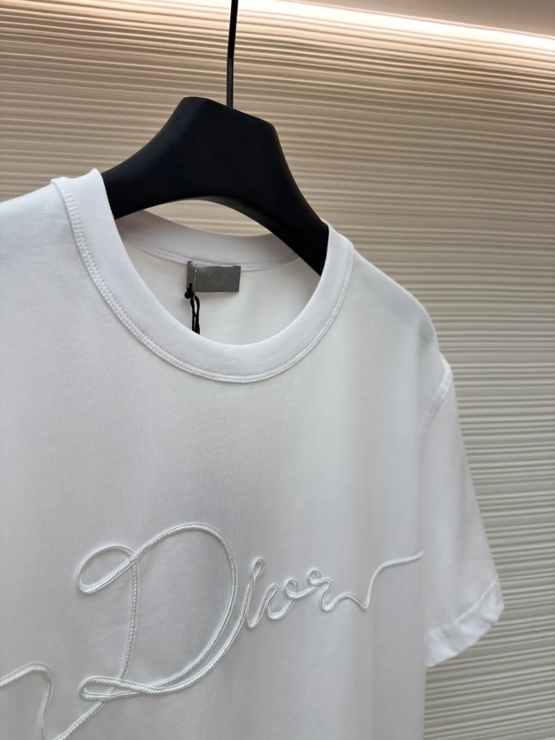 Dior satin emblem round neck short sleeves ●Original version: purchased and developed by 7089 ●Item number: 1681695-A00 ●Fabric: cotton jersey fabric ●Technology: embroidery production ●Color: white ●Version: fitted version ●Weight: about 205 grams ●Size: XS-S-M-L ●Description: The main body is made of 24-count special-spun compact cotton. The weight of 185g/㎡ is light to medium, ensuring the lightness, breathability and good drape of the T-shirt. It is suitable for both spring wear alone and as an inner layer. With 32 pieces of 1×1 rib, 300g/㎡. Its special spinning and compacting process means that compact spinning technology is used in the spinning process, which effectively reduces the hairiness of the yarn, making the yarn smoother and stronger. The woven fabric therefore has the advantages of compact structure, smooth surface, and resistance to pilling. The final dark gray tone is combined with the simple texture of jersey to create a high-end matte texture. Embroidery decoration in the form of satin ribbons, which are fixed on the fabric through special processing. The texture brought by this process is usually different from the woven texture and slight luster of the main knitted fabric. It forms a delicate and accessible visual and tactile focus on the matte dark gray base, enhancing the craftsmanship, design and uniqueness of the single product. The overall wiring is straight and delicate, the fabric is comfortable and soft, and the color is consistent without color difference. It can be matched with the same style to create a fashionable look and control various occasions. Customized accessories, complete with three standards, same style for men and women!