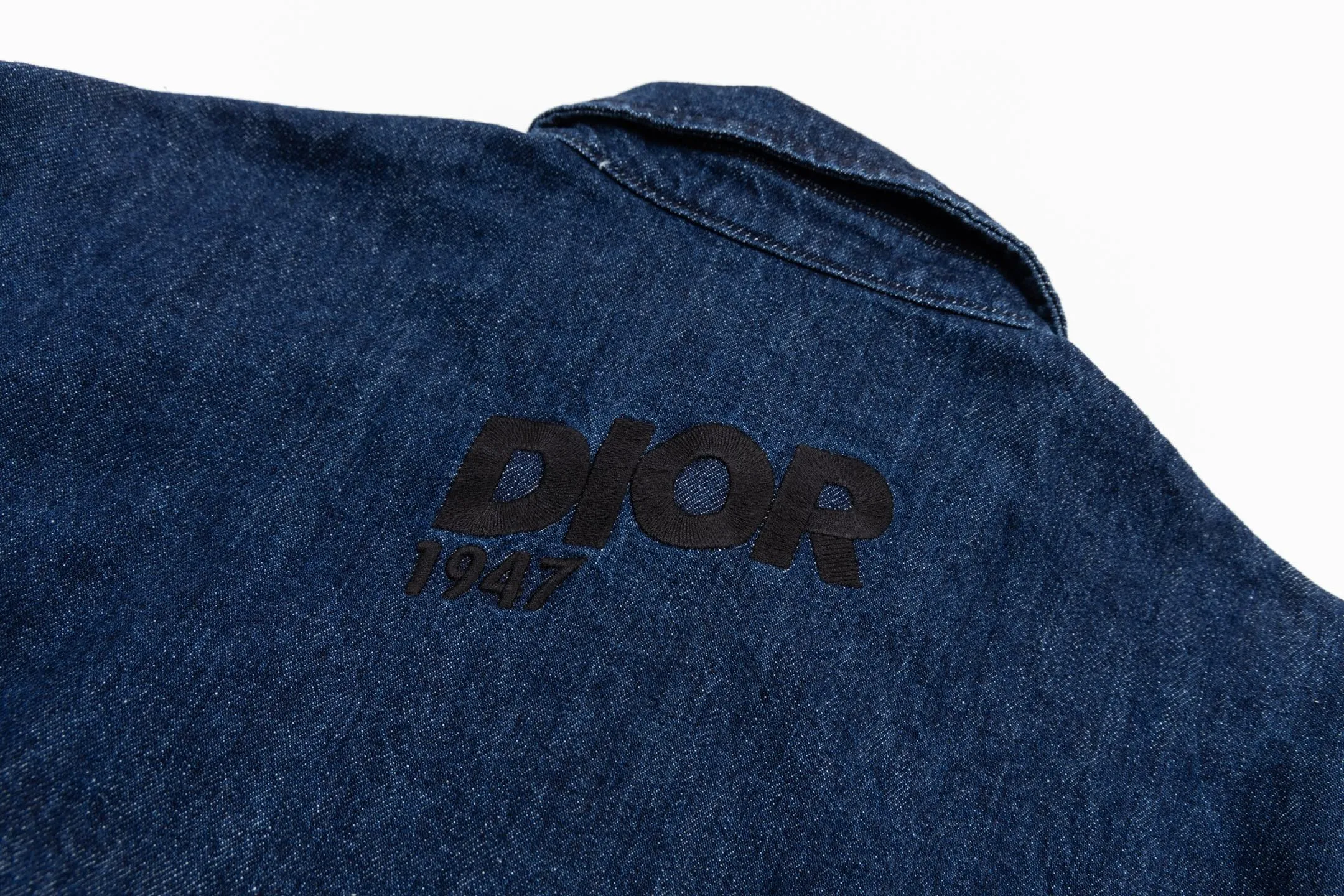 🅿️600 CD 26SS 1947 letter embroidered denim jacket. This jacket shirt is a new product of the 2026 spring men's wear series. It is decorated with multi-color patches, showing the alpine spirit and the classic logo of high-end style inspired by CD archives. Crafted from blue cotton denim for a lightweight feel, it features embroidery on the chest pocket and back. It features a front zipper closure and can be paired with the matching jeans for a sophisticated look. Using high-count cotton denim, through weight reduction textile technology and special washing treatment, while retaining the twill texture and denim durability, the fabric weight has been successfully reduced to the ideal state. The finished product has a cloud-like soft and waxy feel and excellent drape, which subverts the heavy impression of denim. The three-dimensional layering is created through patch pocket technology with a strong hand-feel, and delicate letter outlines are constructed on the chest and back using contrasting embroidery threads and three-dimensional embroidery techniques. The stitch density has been carefully calculated to ensure that the pattern still maintains a high-definition level of clarity despite the rough texture of the denim. The overall structure adopts a jacket-like shirt structure, with precision toothed chain and pull tab design as the opening and closing design, taking into account smooth operation experience and windproof performance. Functional details such as chest patch pockets inside and outside continue the pragmatic logic, and all seam interfaces are secondary reinforced to meet the durability needs of outdoor scenes while maintaining the contours. Size:44-46-48-50