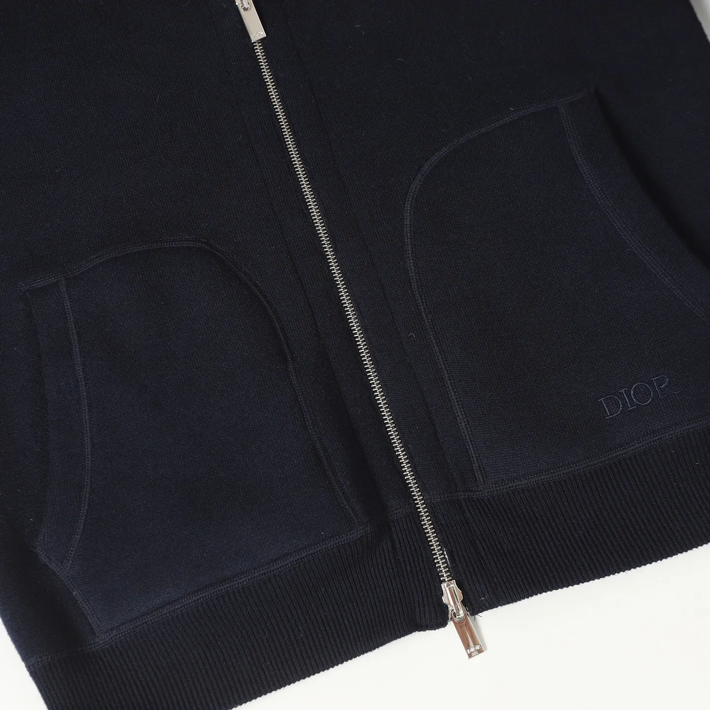 🅿️650 [Original quality] CD/Dior 24FW jacquard double-sided cashmere jacket (navy blue) The fabric is made of cotton and cashmere blended fabrics, and is made of high-quality wool and cashmere, which is soft and comfortable to the touch. The navy blue cotton blended knitted fabric is carefully crafted using imported machine jacquard technology. One side is decorated with the classic presbyopia logo jacquard pattern, and the other side is a simple white design. It can be worn on both sides. The drawstring hood is paired with metal hardware engraved with the Dior logo, adding refined detail. It features practical patch pockets on the front, and a ribbed hem and cuffs ensure a form-fitting fit. The double zipper with monogram highlights the brand's signature, and the raglan sleeves are cut in a smooth, natural style. The front is embellished with the Dior embroidered logo, and the inside is decorated with Oblique print throughout, with exquisite details. Pair with the matching sports trousers for an elegant and casual look. The whole piece integrates high-end craftsmanship into daily items, showing the brand's exquisite craftsmanship and classic aesthetics. Size:S/M/L/XL