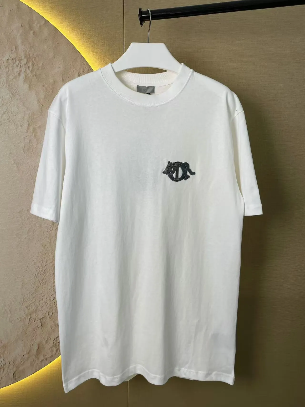 🅿️170 Dior Patch Letter Short Sleeve Color: navy blue (new custom dyed color), apricot, white, size S-XL, made of pure cotton 12S fine cotton plain weave, weight 260g. The front is decorated with contrasting logo patches and small embroidered stamps, forming a decorative and iconic embroidery product. The logo is made of imported custom-made embroidery thread, which is dyed with lustrous mercerized embroidery thread, giving it a uniform and glossy finish. The exquisite embroidery machine combines complex embroidery needlework and fine detail processing to create a three-dimensional micro-relief embroidery effect; at the same time, it is highly durable and wear-resistant. The standard round neck short-sleeved version, with a rounded arc neckline, is suitable for various face shapes and body shapes; the moderate sleeve length ends just above the elbow, showing a smart and neat image. The slim fit can show off the wearer's body curves without sacrificing comfort. The collar, cuffs, hem and other parts are all sewn with fine double-needle stitching.  size：xs s m l