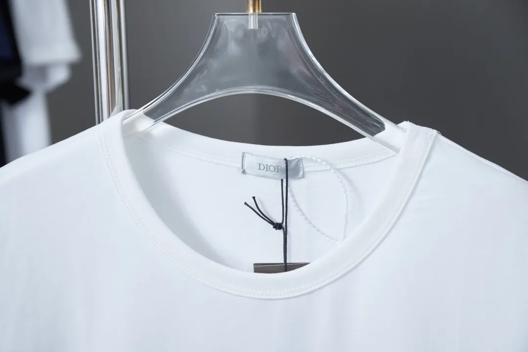 🅿️200 High Quality This T-shirt is decorated with Dior Charm logo print and embroidery, paying tribute to Dior's classic logo. Crafted from white cotton jersey with a classic ribbed crew neck. Casual and versatile, it can be paired with a variety of casual outfits to create a sophisticated look. In the penetration glue printing process, printing dyes and chemical gels are required to ensure that the printing effect is bright and strong. At the same time, in order to obtain better penetration effect, the glue has very good coverage and has a certain gloss. Combined with the patch printing process, patch embroidery, also known as applique embroidery, is a form of embroidery in which other fabrics are cut and sewn onto clothing. The stitching method is used to lock the edges so that the threads or rough areas on the outer edge of the fabric are not exposed, highlighting the styling. S M L XL S M L XL