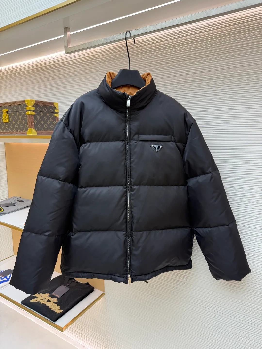 Prada logo stand collar down jacket ●Item number: 1681794-C75 ●Material: white duck down fabric ●Technology: mechanical down filling ●Color: black ●Version: fitted version ●Weight: about 855 grams ●Size: S-M-L-XL ●Description: The recycled nylon fabric made of 100% nylon is woven into a tight and tough fabric through advanced textile technology. The strength of the frame is increased to effectively block the invasion of cold wind and lock the warm air generated by the down layer. After a tight weaving process and special treatment, it is waterproof and windproof. The surface forms a certain lotus leaf effect. It is also anti-wrinkle and not easy to deform, making it easy for daily care. The inner lining is made of caramel brown nylon fabric woven from 100% polyamide. When folded, it creates a strong color contrast, just like the molten gold of the setting sun pouring into the deep night sky. Polyamide fiber is known for its extremely high strength and excellent skin-friendly feel. It feels silky smooth and avoids the friction and discomfort that may occur when wearing heavy underwear. It works together with the outer layer of nylon to create a breathable, temperature-locking, and extremely comfortable microclimate environment, allowing warmth and care to be online at all times without feeling stuffy or restrictive. It uses 90 white duck down with a fill power of 220g to ensure excellent thermal insulation performance. After the velvet has been strictly screened and processed, it is not easy to drill. The 6cm tall stand-up collar fits the neck line without being oppressive, and is as warm as a "second skin" in the cold wind. The junction between the collar and the zipper adopts a bevel splicing process to avoid the rigid feeling of traditional stand-up collars and make it more flexible when you turn your head. The hem has built-in metal adjustment buckles on both sides. You can gently pull it down to tighten the waistline, and lift it up to restore the loose silhouette - it is neat and slim when commuting, and it is free and unrestrained when outdoors. The metal surface of the adjustment buckle is treated with PVD coating, which is wear-resistant and corrosion-resistant, and will last forever. The overall wiring is straight and delicate, the fabric is comfortable and soft, and the color is consistent without color difference. It can be matched with the same style to create a fashionable look and control various occasions. Customized accessories, complete with three standards, same style for men and women!