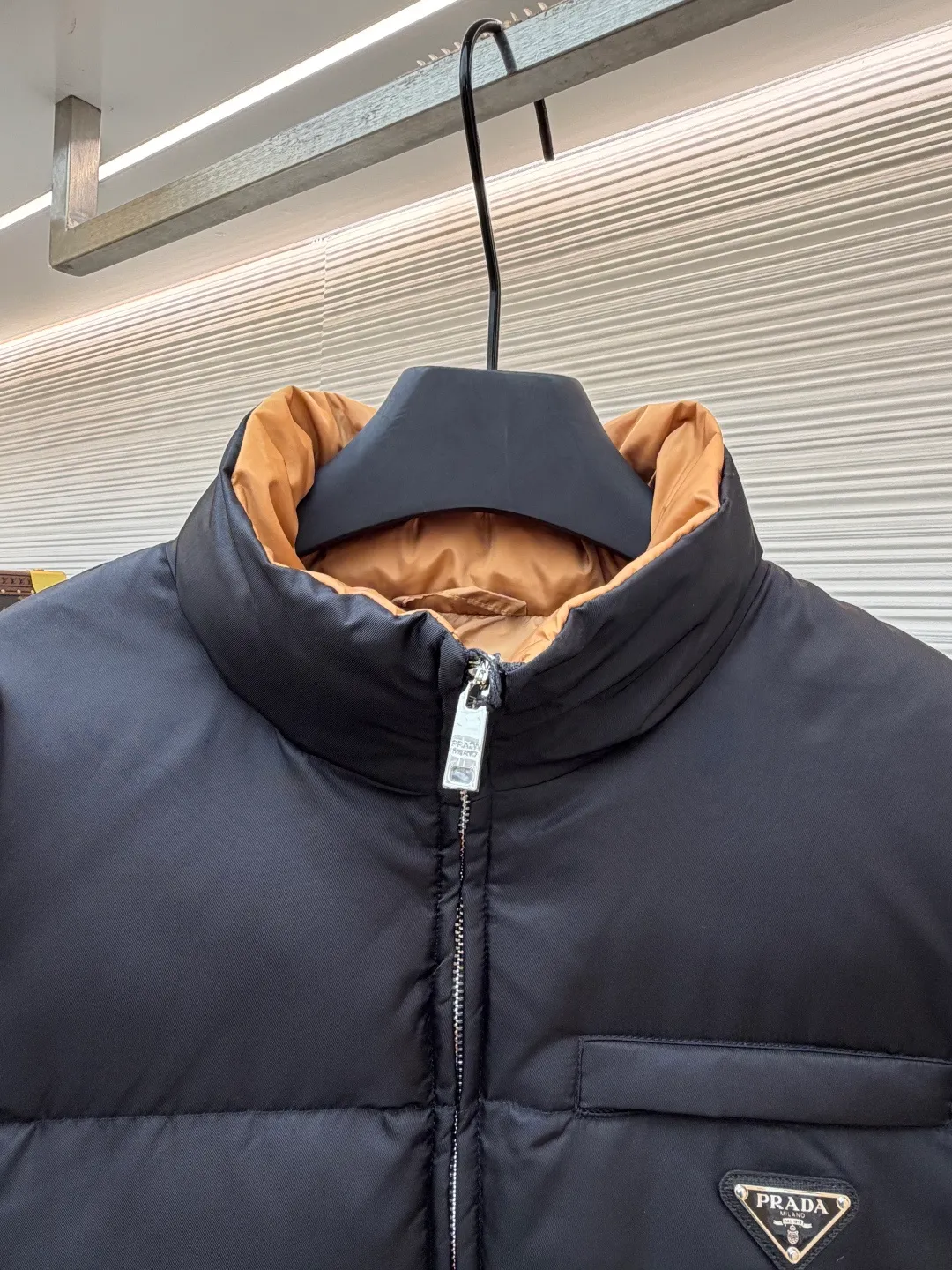 Prada logo stand collar down jacket ●Item number: 1681794-C75 ●Material: white duck down fabric ●Technology: mechanical down filling ●Color: black ●Version: fitted version ●Weight: about 855 grams ●Size: S-M-L-XL ●Description: The recycled nylon fabric made of 100% nylon is woven into a tight and tough fabric through advanced textile technology. The strength of the frame is increased to effectively block the invasion of cold wind and lock the warm air generated by the down layer. After a tight weaving process and special treatment, it is waterproof and windproof. The surface forms a certain lotus leaf effect. It is also anti-wrinkle and not easy to deform, making it easy for daily care. The inner lining is made of caramel brown nylon fabric woven from 100% polyamide. When folded, it creates a strong color contrast, just like the molten gold of the setting sun pouring into the deep night sky. Polyamide fiber is known for its extremely high strength and excellent skin-friendly feel. It feels silky smooth and avoids the friction and discomfort that may occur when wearing heavy underwear. It works together with the outer layer of nylon to create a breathable, temperature-locking, and extremely comfortable microclimate environment, allowing warmth and care to be online at all times without feeling stuffy or restrictive. It uses 90 white duck down with a fill power of 220g to ensure excellent thermal insulation performance. After the velvet has been strictly screened and processed, it is not easy to drill. The 6cm tall stand-up collar fits the neck line without being oppressive, and is as warm as a "second skin" in the cold wind. The junction between the collar and the zipper adopts a bevel splicing process to avoid the rigid feeling of traditional stand-up collars and make it more flexible when you turn your head. The hem has built-in metal adjustment buckles on both sides. You can gently pull it down to tighten the waistline, and lift it up to restore the loose silhouette - it is neat and slim when commuting, and it is free and unrestrained when outdoors. The metal surface of the adjustment buckle is treated with PVD coating, which is wear-resistant and corrosion-resistant, and will last forever. The overall wiring is straight and delicate, the fabric is comfortable and soft, and the color is consistent without color difference. It can be matched with the same style to create a fashionable look and control various occasions. Customized accessories, complete with three standards, same style for men and women!