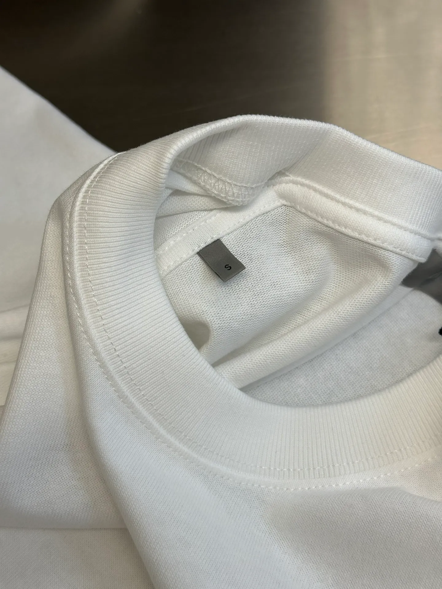 🅿️260 Dior patch letter short sleeves are made of pure cotton 12S fine cotton plain weave, weight 230g. The front is decorated with contrasting logo patches and small embroidered stamps, forming a decorative and iconic embroidery product. The logo is made of imported custom-made embroidery thread, which is dyed with lustrous mercerized embroidery thread, giving it a uniform and glossy finish. The exquisite embroidery machine combines complex embroidery needlework and fine detail processing to create a three-dimensional micro-relief embroidery effect; it is also highly durable and wear-resistant.  The standard round neck and short-sleeved version has a rounded arc neckline, which is suitable for various face shapes and body shapes; the sleeve length is moderate and ends just above the elbow, showing a smart and neat image. The slim fit can show off the wearer's body curves without sacrificing comfort. The collar, cuffs, hem and other parts are all sewn with fine double-needle stitching.  size：xs s m l