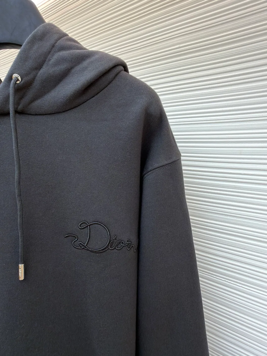 Dior woven satin badge hooded sweatshirt ●Item number: 1681708-A90 ●Material: Cotton pile terry fabric ●Technology: Ribbon letter embroidery production ●Color: gray ●Version: fitted version ●Weight: about 760 grams ●Size: XS-S-M-L ●Description: The pure cotton texture fabric is made of 26-count double yarn + 10-count bottom yarn terry fabric, with a weight of 380g/㎡; it is paired with 21-count 2x2 rib, and the composition is 95% cotton and 5% spandex. The multi-dimensional texture brought by the craftsmanship. The ribbon itself has a silky luster and smooth touch, which is in sharp and high-end contrast with the matte plush feel of the sweatshirt's suede surface. Embroidery decoration in the form of satin ribbons, which are fixed on the fabric through special processing. The texture brought by this process is usually different from the woven texture and slight luster of the main knitted fabric. It forms a delicate and accessible visual and tactile focus on the matte dark gray base, enhancing the craftsmanship, design and uniqueness of the single product. The overall wiring is straight and delicate, the fabric is comfortable and soft, and the color is consistent without color difference. It can be matched with the same style to create a fashionable look and control various occasions. Customized accessories, complete with three standards, same style for men and women!