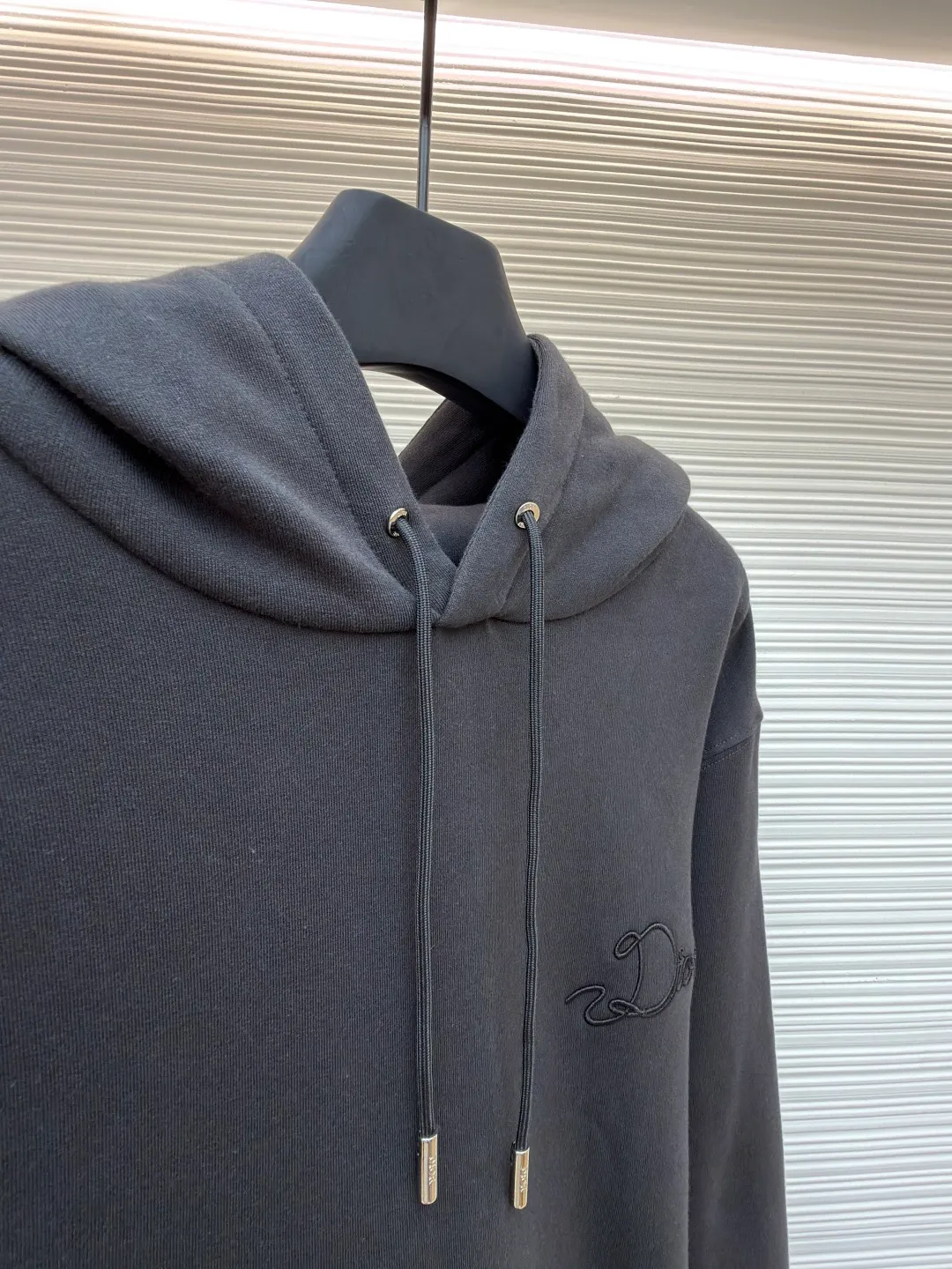 Dior woven satin badge hooded sweatshirt ●Item number: 1681708-A90 ●Material: Cotton pile terry fabric ●Technology: Ribbon letter embroidery production ●Color: gray ●Version: fitted version ●Weight: about 760 grams ●Size: XS-S-M-L ●Description: The pure cotton texture fabric is made of 26-count double yarn + 10-count bottom yarn terry fabric, with a weight of 380g/㎡; it is paired with 21-count 2x2 rib, and the composition is 95% cotton and 5% spandex. The multi-dimensional texture brought by the craftsmanship. The ribbon itself has a silky luster and smooth touch, which is in sharp and high-end contrast with the matte plush feel of the sweatshirt's suede surface. Embroidery decoration in the form of satin ribbons, which are fixed on the fabric through special processing. The texture brought by this process is usually different from the woven texture and slight luster of the main knitted fabric. It forms a delicate and accessible visual and tactile focus on the matte dark gray base, enhancing the craftsmanship, design and uniqueness of the single product. The overall wiring is straight and delicate, the fabric is comfortable and soft, and the color is consistent without color difference. It can be matched with the same style to create a fashionable look and control various occasions. Customized accessories, complete with three standards, same style for men and women!