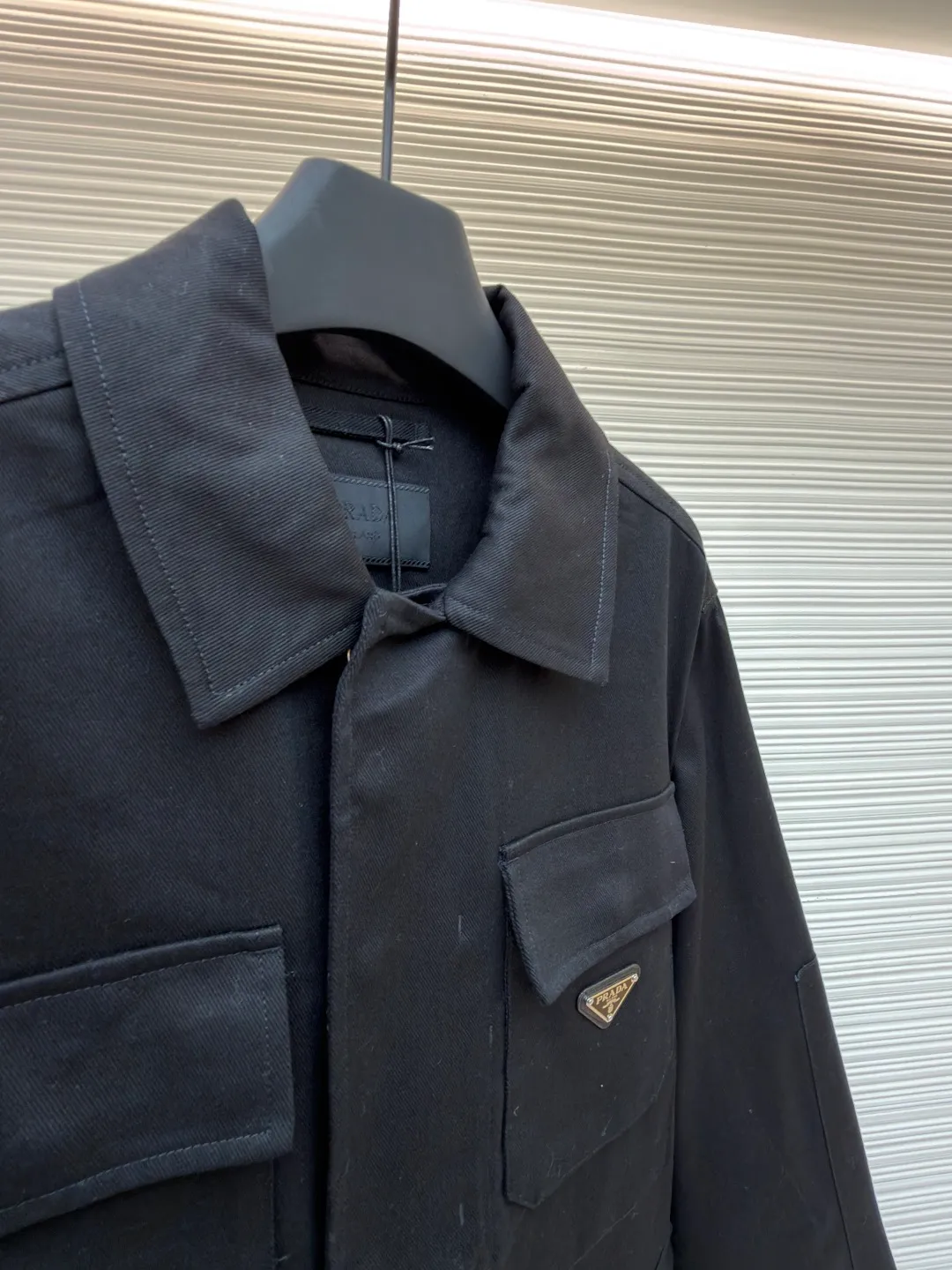 PRADA cotton work style jacket ●Original version: Purchased and developed by 14803 ●Item number: 1680864-B90 ●Fabric: nylon fabric ●Technology: Made on positioning cutting machine ●Version: fitted version ●Weight: about 760 grams ●Size: S-M-L-XL ●Description: The fabric is constructed with 45° diagonal warp and weft interweaving, and the closely arranged cotton yarns form a natural three-dimensional texture, giving it a practical base that is anti-wrinkle and wear-resistant. At the same time, the matte texture echoes the rough aesthetics of workwear style. It retains the natural skin-friendliness and sweat-absorbing ability of cotton fiber, while taking into account warmth and breathability. Utilizing the natural stiffness of the fabric, double-layer cotton yarn is used to reinforce the shoulder seams to create a sculptural wide shoulder silhouette and avoid softness and deformation. Invisible thread strips are embedded in the cuffs to ensure freedom of movement. Through low-temperature pressing and the natural hardness of twill fabric, a 30-degree stiffening angle is created to make the neckline fit the curve of the neck and improve wearing comfort. Abandoning the traditional lining, the stiffness of the fabric itself is used to shape the silhouette, reducing redundant layers while improving breathability. Hidden button closure and straight bottom hem design enhance the tough temperament and balance the loose fit, avoiding a bloated look. Symmetrical flap patch pockets enhance practicality, and the three-dimensional silhouette adds a sense of hierarchy. Tight stitching at the edges makes the bag sturdy while adding beauty. The overall wiring is straight and delicate, the fabric is comfortable and soft, and the color is consistent without color difference. It can be matched with the same style to create a fashionable look and control various occasions. Customized accessories, complete with three standards, same style for men and women!