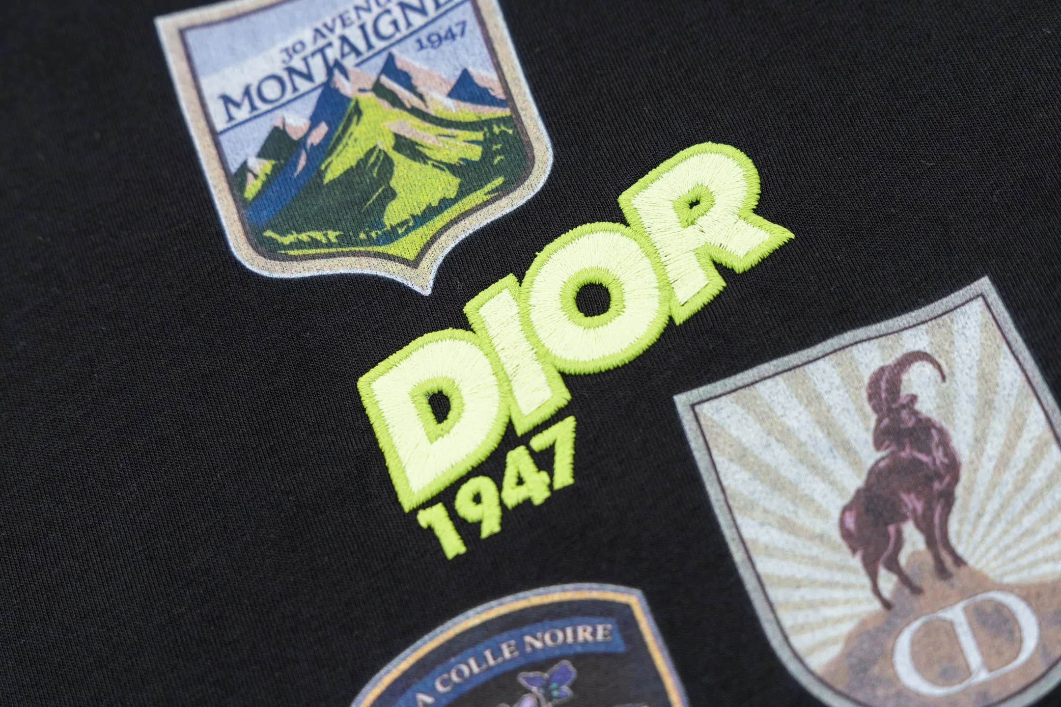 🅿️280 CD Mountain Alpine Shield Print Short Sleeve (Black) The fabric is made of 24S 185g special woven compact cotton fabric, and the rib is made of 32S 300g double yarn rib. This Mountain T-shirt is a new product of the 2026 spring men's wear series. It is decorated with multi-color patches to show the mountain spirit and the classic logo of high-end style inspired by archives. Crafted from white cotton jersey, it features a crew neck for a refined look. The fabric is made of 24S special-spun compact cotton as a plain knitted base. The high-count compact spinning process ensures that the fabric has an extremely delicate skin feel and excellent anti-pilling durability. The neckline is equipped with 32S 1x1 high-density ribbing, which provides long-lasting rebound with its tight structure and protects the collar shape. The decorative multi-color embroidery patch adopts appliqué technique. Three-dimensional lines and fluorescent details are first embroidered with high-density stitches on independent fabrics, and then accurately covered on the chest, forming a strong visual hierarchy and tactile contrast. The alpine element pattern uses digital white ink direct injection technology, with saturated colors and sharp edges, which together with the embroidery patch create a rich texture. Size:XS-S-M-L