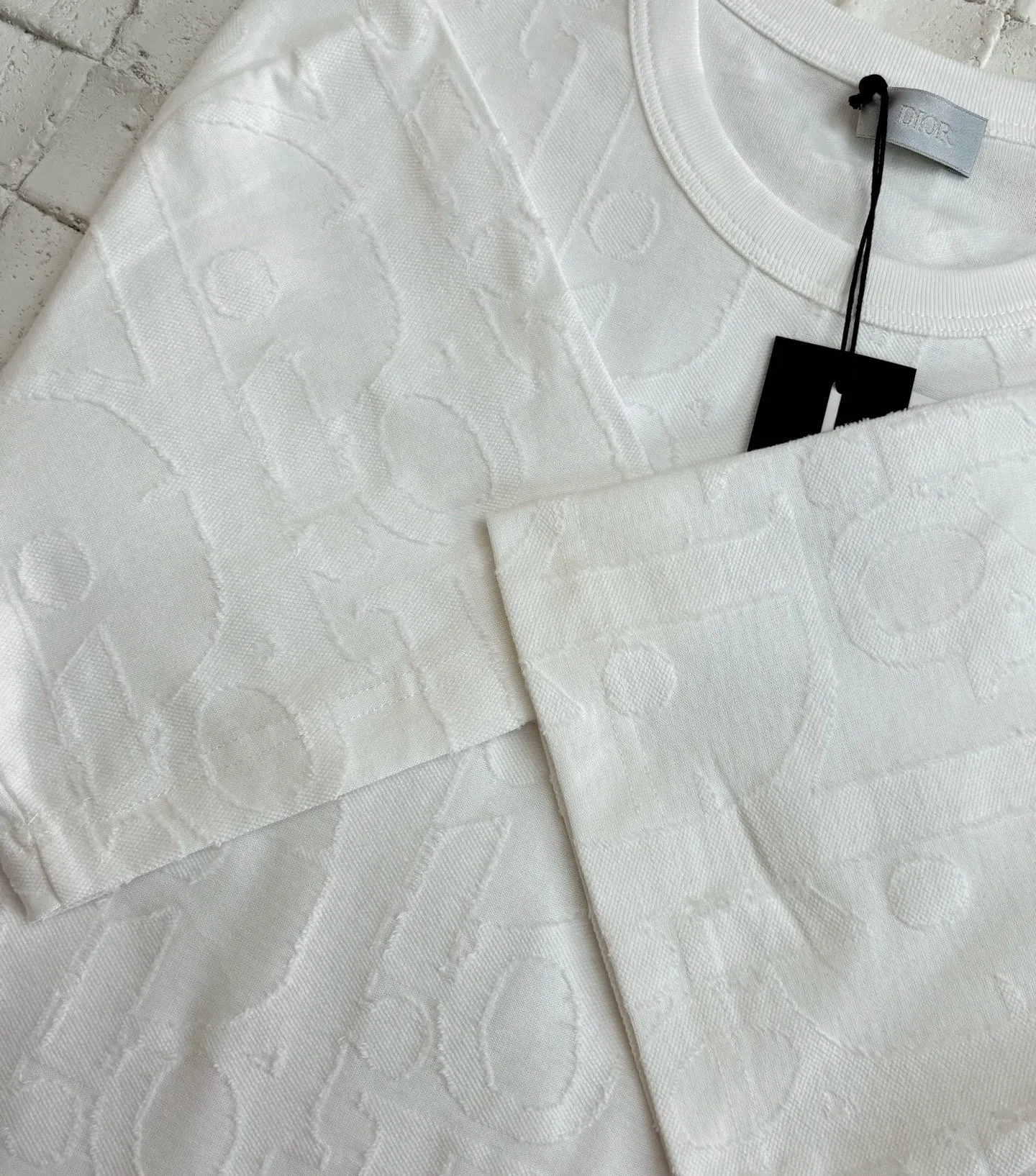 🅿️296 Dio*/Dior 25Ss new line-cut jacquard round-neck short-sleeved T-shirt. Pure cotton plain weave fabric, woven with 32S double-ply pure cotton yarn. The fabric has high abrasion resistance while retaining the moisture absorption and breathability of pure cotton. The plain weave has a tight structure and a smooth surface, but it feels relatively stiff and supports the stiffness of the version. Jacquard pattern, line-cut jacquard technology, full-width Oblique jacquard pattern The relief effect is formed through the deep integration of full-width jacquard and shearing process. The jacquard structure provides a three-dimensional skeleton, and the shearing process strengthens the local texture. Electronic jacquard machine weaves complex patterns on the entire fabric, forming a three-dimensional concave and convex texture to achieve the integration of texture and pattern. The raised jacquard is directionally sheared to form a relief effect, enhancing the tactile level and visual contrast. Size: S/M/L/XL