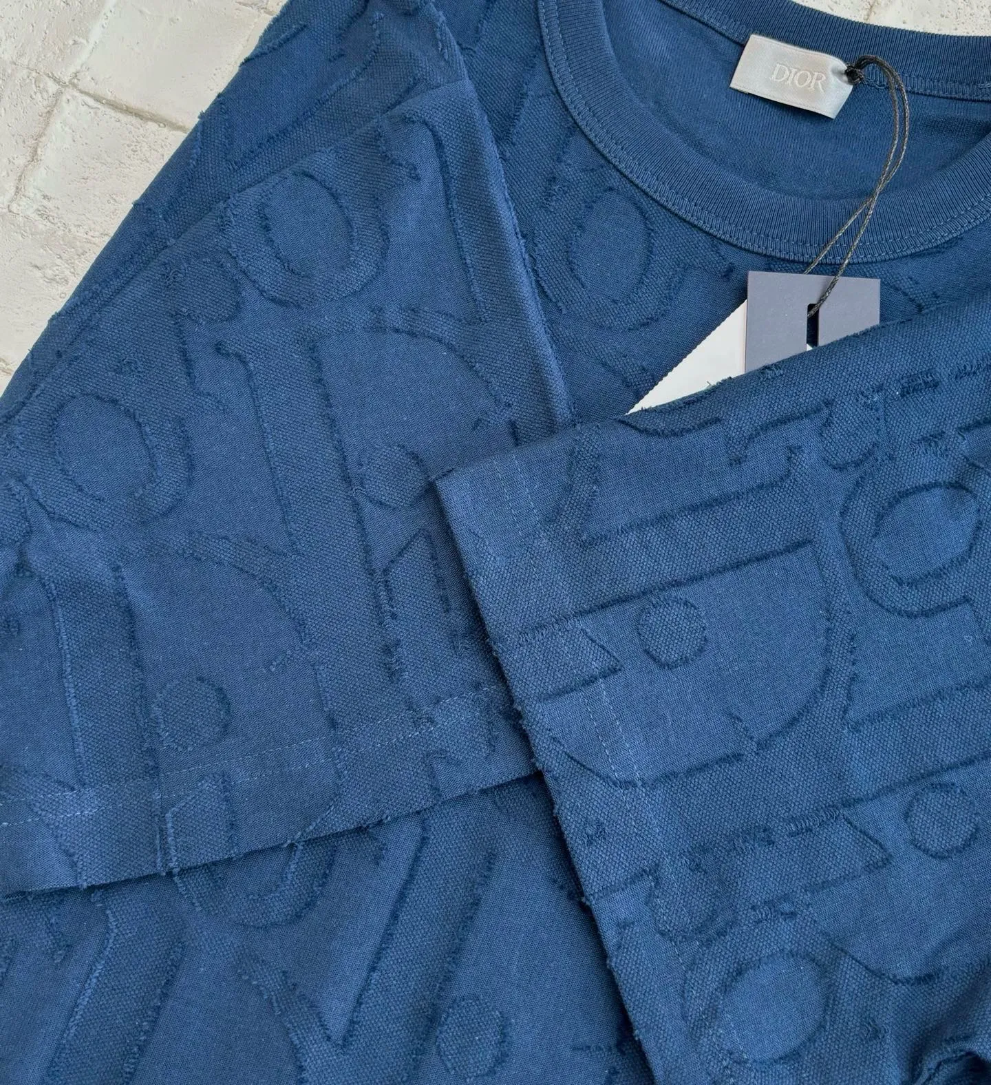 🅿️296 Dio*/Dior 25Ss new line-cut jacquard round-neck short-sleeved T-shirt. Pure cotton plain weave fabric, woven with 32S double-ply pure cotton yarn. The fabric has high abrasion resistance while retaining the moisture absorption and breathability of pure cotton. The plain weave has a tight structure and a smooth surface, but it feels relatively stiff and supports the stiffness of the version. Jacquard pattern, line-cut jacquard technology, full-width Oblique jacquard pattern The relief effect is formed through the deep integration of full-width jacquard and shearing process. The jacquard structure provides a three-dimensional skeleton, and the shearing process strengthens the local texture. Electronic jacquard machine weaves complex patterns on the entire fabric, forming a three-dimensional concave and convex texture to achieve the integration of texture and pattern. The raised jacquard is directionally sheared to form a relief effect, enhancing the tactile level and visual contrast. Size: S/M/L/XL
