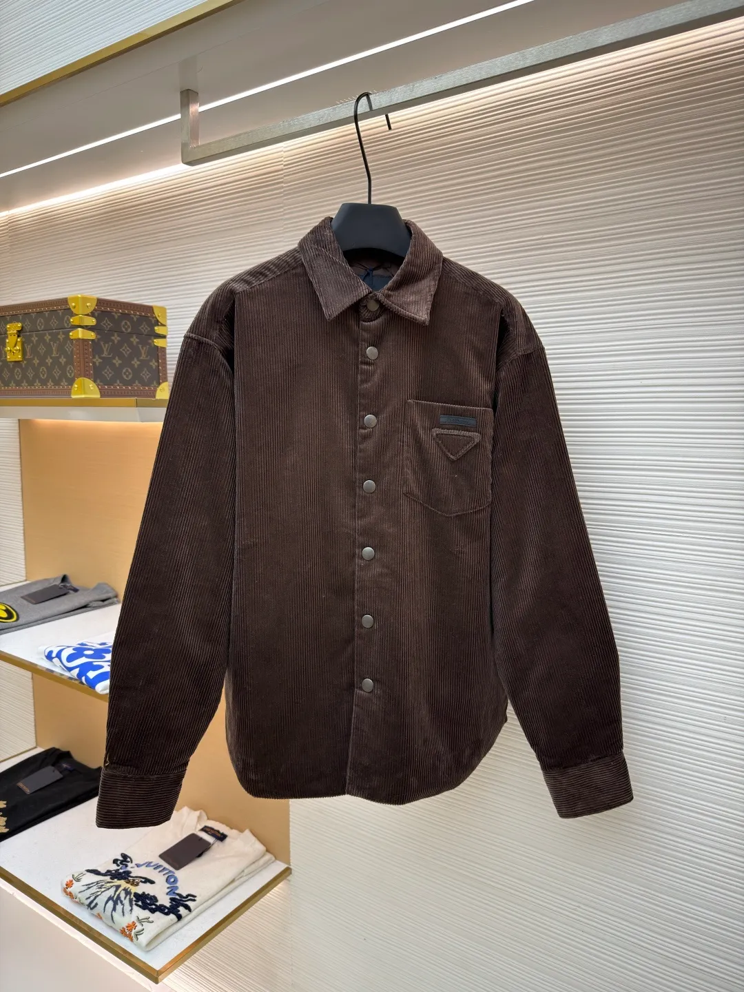 Prada triangle logo corduroy cotton jacket ●Original version: purchased and developed by 10012 ●Item number: 1682236-B90 ●Fabric: corduroy fabric ●Technology: made on positioning cutting machine ●Color: brown ●Version: fitted version ●Weight: about 745 grams ●Size: XS-S-M-L ●Description: This brown corduroy shirt-style jacket is made of high-count combed cotton corduroy fabric. It has been treated with pre-washing water. The fabric velvet is even in thickness, soft and waxy to the touch, and not easy to pill and deform. It also has good drape and wrinkle resistance. The body is cut into a loose shirt silhouette, and the shoulders are designed with natural dropped shoulders. Combined with three-dimensional tailoring technology, the shape is more ergonomic. The placket is made of matte metal snaps, treated with anti-oxidation plating, which makes it high-quality and durable. The triangular patch pocket on the chest is equipped with the brand's metal logo plate, which is fixed with manual caulking and has neat edges. The collar and cuffs are double-layered and reinforced, the sewing stitches are fine and even, and the spacing of each inch of stitches is strictly controlled. The overall workmanship combines practicality and exquisiteness, fully demonstrating the craftsmanship. The overall wiring is straight and delicate, the fabric is comfortable and soft, and the color is consistent without color difference. It can be matched with the same style to create a fashionable look and control various occasions. Customized accessories, complete with three standards, same style for men and women!