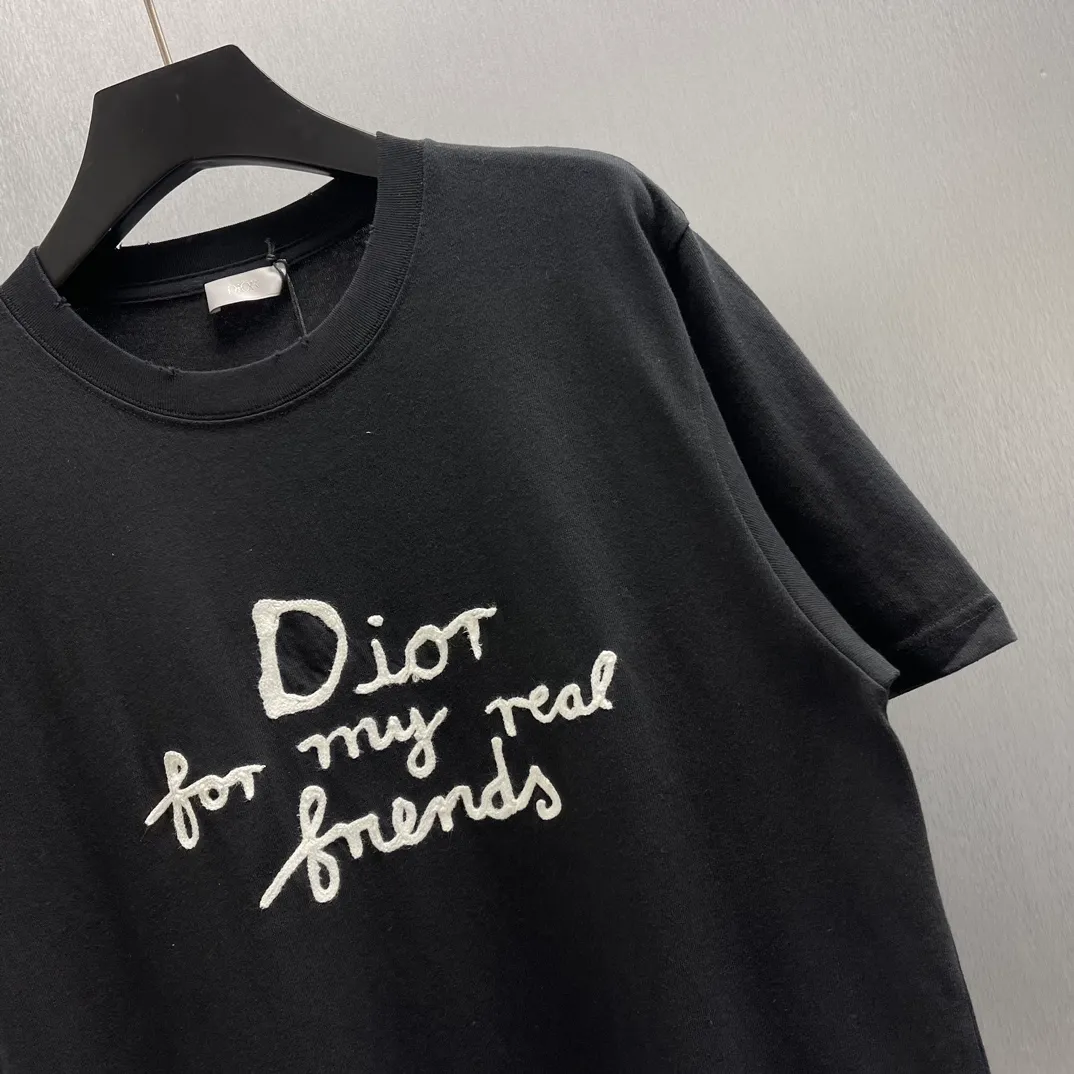 🅿️260 🧧CD True Friends Private Lettered Short Sleeves Size: S-XL This T-shirt displays the Dior For My Real Friends logo from the DIOR AND HYLTON NEL joint series. Crafted from black cotton jersey, it features a classic silhouette with a ribbed crew neck, embroidery on the chest for added style, and a burned-out effect on the collar, sleeves and hem. Cut for a relaxed fit, wear it with track pants or jeans.