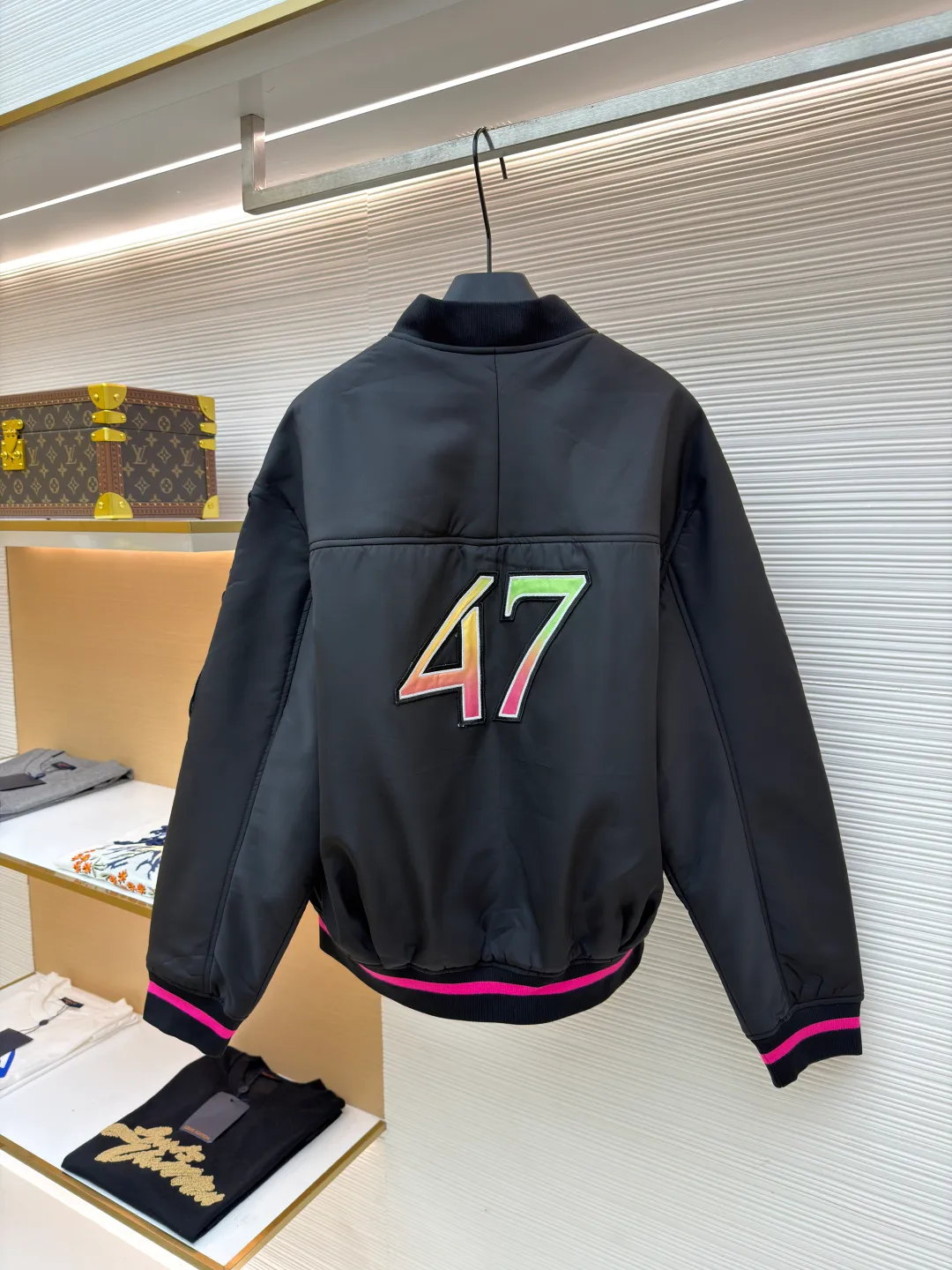Dior Hamilton joint baseball uniform ●Original version: 32000 purchased and developed ●Item number: 1681336-B90 ●Fabric: nylon fabric ●Technology: printing production ●Color: black ●Version: fitted version ●Weight: about 830 grams ●Size: 48-50-52-54 ●Description: Made of high-quality matte nylon fabric, the texture is stiff and windproof. It has been treated with a special coating to improve wear resistance and texture, and provide good shape support for the jacket. The colorful letter pattern on the sleeves uses a multi-layer offset printing process, with natural color gradients and strong adhesion; the "DIOR 47" logo on the chest is precision embroidered, with fine stitching and high integration with the fabric, highlighting the brand's craftsmanship. Made from a classic baseball uniform cut, the silhouette is sleek and stylish. Double thread reinforcement is used during sewing, the seams are smooth and snug, the stitch spacing is even, and the lines are straight, reflecting the rigorous garment making process. The zipper is a brand-customized metal zipper with brand details on the zipper puller, which is smooth and durable; the ribbed collar, cuffs and hem are made of high-elastic knitting technology, which has good elasticity, is comfortable to wear and can effectively prevent wind. The pockets on both sides are designed as hidden pockets, which are practical while maintaining overall beauty; the pink trim on the body contrasts sharply with the main black tone, and the craftsmanship details reflect the brand's high-end production standards.