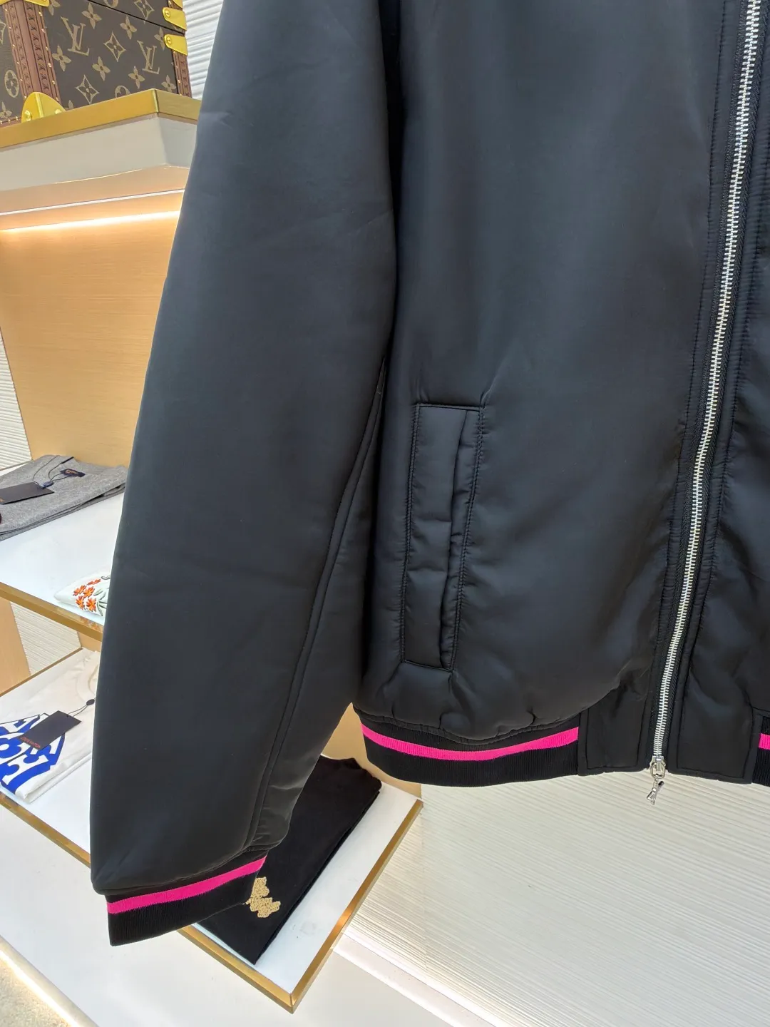 Dior Hamilton joint baseball uniform ●Original version: 32000 purchased and developed ●Item number: 1681336-B90 ●Fabric: nylon fabric ●Technology: printing production ●Color: black ●Version: fitted version ●Weight: about 830 grams ●Size: 48-50-52-54 ●Description: Made of high-quality matte nylon fabric, the texture is stiff and windproof. It has been treated with a special coating to improve wear resistance and texture, and provide good shape support for the jacket. The colorful letter pattern on the sleeves uses a multi-layer offset printing process, with natural color gradients and strong adhesion; the "DIOR 47" logo on the chest is precision embroidered, with fine stitching and high integration with the fabric, highlighting the brand's craftsmanship. Made from a classic baseball uniform cut, the silhouette is sleek and stylish. Double thread reinforcement is used during sewing, the seams are smooth and snug, the stitch spacing is even, and the lines are straight, reflecting the rigorous garment making process. The zipper is a brand-customized metal zipper with brand details on the zipper puller, which is smooth and durable; the ribbed collar, cuffs and hem are made of high-elastic knitting technology, which has good elasticity, is comfortable to wear and can effectively prevent wind. The pockets on both sides are designed as hidden pockets, which are practical while maintaining overall beauty; the pink trim on the body contrasts sharply with the main black tone, and the craftsmanship details reflect the brand's high-end production standards.