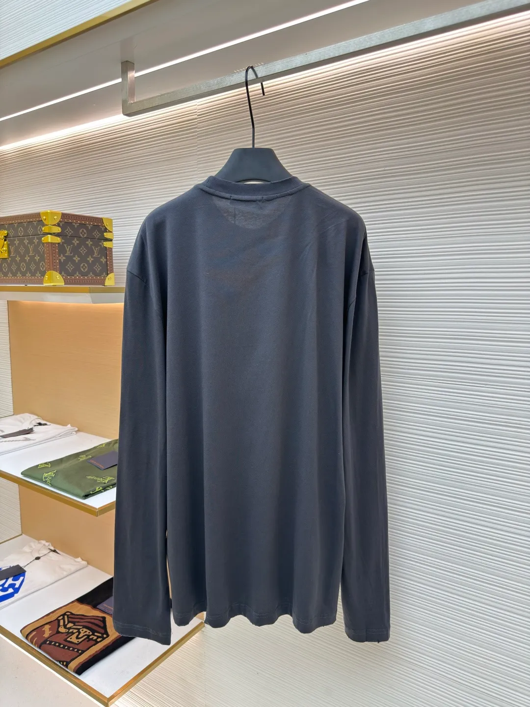 Prada Pencil Gray Long Sleeve ●Original version: Purchased and developed by 8934 ●Item number: 1680720-A05 ●Fabric: combed plain weave fabric ●Technology: Laser burning ●Version: fitted version ●Weight: about 240 grams ●Size: S-M-L-XL ●Description: Custom-woven 50S 190G combed plain weave fabric, non-market general gray fabric, needs to be fully customized from yarn ratio and loom parameters. Short fiber impurities are removed through the combing process to ensure that the yarn is longer and more uniform, and the fabric surface is smooth and hairless.  Specially dyed pencil gray, the color is adjusted individually instead of using a standard color card. Multiple proofing is required to match the low saturation gray tone specified by Prada. Chest triangle laser burnt embroidery shaping: Laser burnt: high-precision laser engraving, carbonizing the fabric surface to form a gradient etching texture, and the edges need to be manually adjusted to avoid scorch marks.  Composite embroidery: superimpose embroidery on the basis of burnt flowers. The stitch density needs to be aligned with the burnt flowers pattern to prevent fabric deformation.  Three-dimensional shaping: Use high-temperature pressing or resin coating to maintain the relief of the triangular structure and avoid collapse after washing. The overall wiring is straight and delicate, the fabric is comfortable and soft, and the color is consistent without color difference. It can be matched with the same style to create a fashionable look and control various occasions. Customized accessories, complete with three standards, same style for men and women!