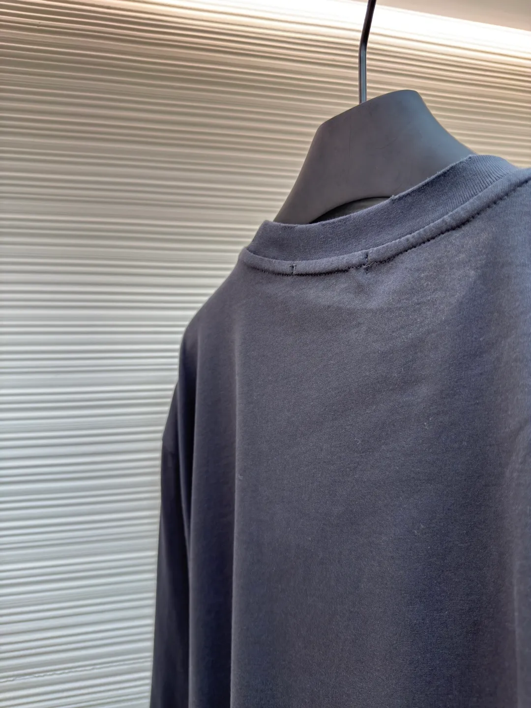 Prada Pencil Gray Long Sleeve ●Original version: Purchased and developed by 8934 ●Item number: 1680720-A05 ●Fabric: combed plain weave fabric ●Technology: Laser burning ●Version: fitted version ●Weight: about 240 grams ●Size: S-M-L-XL ●Description: Custom-woven 50S 190G combed plain weave fabric, non-market general gray fabric, needs to be fully customized from yarn ratio and loom parameters. Short fiber impurities are removed through the combing process to ensure that the yarn is longer and more uniform, and the fabric surface is smooth and hairless.  Specially dyed pencil gray, the color is adjusted individually instead of using a standard color card. Multiple proofing is required to match the low saturation gray tone specified by Prada. Chest triangle laser burnt embroidery shaping: Laser burnt: high-precision laser engraving, carbonizing the fabric surface to form a gradient etching texture, and the edges need to be manually adjusted to avoid scorch marks.  Composite embroidery: superimpose embroidery on the basis of burnt flowers. The stitch density needs to be aligned with the burnt flowers pattern to prevent fabric deformation.  Three-dimensional shaping: Use high-temperature pressing or resin coating to maintain the relief of the triangular structure and avoid collapse after washing. The overall wiring is straight and delicate, the fabric is comfortable and soft, and the color is consistent without color difference. It can be matched with the same style to create a fashionable look and control various occasions. Customized accessories, complete with three standards, same style for men and women!