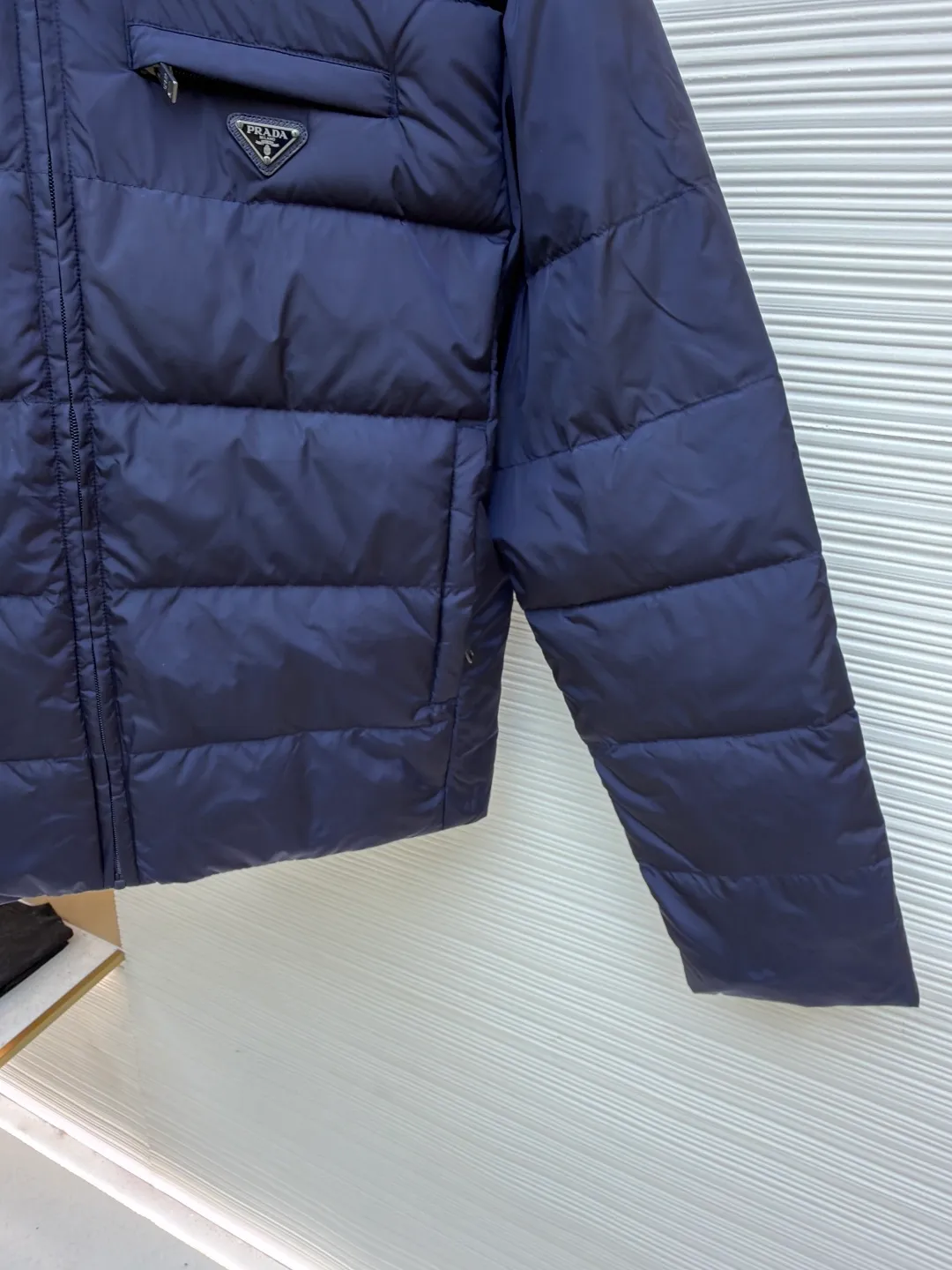 Prada triangle pocket down jacket ●Original version: Purchased and developed in 19800 ●Item number: 1681903-D20 ●Fabric: white duck down fabric ●Technology: mechanical down filling ●Color: navy blue ●Version: fitted version ●Weight: about 675 grams ●Size: 46-48-50-52 ●Description: Customized ultra-dense round hole woven fabric (with anti-repellent treatment) showing a matte micro-texture Use the new national standard 90 white duck down (welcome to test), full of down, full of warmth, you are in a warm cloud, surrounded by soft warmth, the classic black tone exudes an innate sense of luxury, the iconic enameled metal triangle logo is embellished on the chest, low-key and powerful, the stand-up collar is crisp and stylish, accurately fits the neck curve, and uses architectural lines to reconstruct the warmth and neatness of the bloated down jacket. Enjoy warmth and comfort. Become the most considerate companion for mechanical down filling in winter. Prioritize the filling area by making the liner pattern to determine the gram weight of down per square meter according to the original three-dimensional effect, thereby calculating the filling amount of each piece. The computer down filling machine uses a digital weighing unit to achieve stable measurement, and uses imported special machine infrared to locate the "Prada triangle mark" for more accurate positioning. The firm and strong template machine opens the zipper bag. The lines are smooth and tidy. The wiring is even and the template machine lines the lines. The line process of the computer template machine shows extremely high neatness and smoothness. The craftsman accurately controls the size during the operation to ensure that each line meets the design requirements. The lines of the entire template are smooth and uniform, clean and beautiful. The overall wiring is straight and delicate, the fabric is comfortable and soft, and the color is consistent without color difference. It can be matched with the same style to create a fashionable look and control various occasions. Customized accessories, complete with three standards, same style for men and women!
