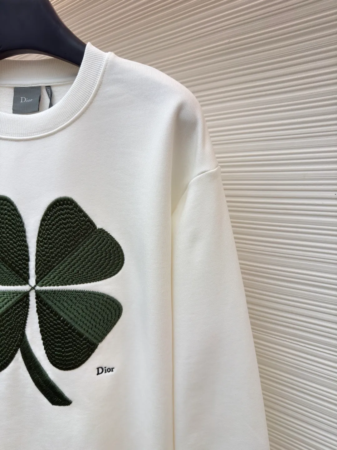 Dior four-leaf clover round neck sweatshirt ●Original version: purchased and developed by 19189 ●Item number: 1682447-A55 ●Material: pure cotton terry bottom sweatshirt fabric ●Technology: hollow embroidery production of coarse wool yarn ●Color: white ●Version: fitted version ●Weight: about 565 grams ●Size: XS-S-M-L ●Description: It adopts a fleece fabric structure of 26-count double yarn surface + 10-count yarn bottom, with a weight of 380g/㎡; with the same weight of 21-count 1x1 rib 470g/㎡. The 26-count double yarn forms a smooth and dense outer surface, and the 10-count yarn base is precisely brushed to form a rich and uniform velvet layer, thereby simultaneously achieving a crisp and skeletal feel on the outside and a skin-friendly touch like cloud velvet on the inside. Ribbing is used on the collar, cuffs and hem. Its extremely high weight and density ensure the ultimate thickness, resilience and deformation resistance of these closing parts, and together with the body, create a full and three-dimensional silhouette. The white color highlights the pure and delicate texture of the fabric and the pile loop texture on the bottom. The Dior Clover embroidery on the front uses hollow embroidery technology of coarse wool yarn. Refers to the use of special embroidery thread that is thicker and may have a plush texture. Its function is to give the embroidery pattern a unique fluffy, three-dimensional and soft touch, imitating the effect of wool weaving or tufting. This is an embroidery technique that uses specific stitches to make embroidery threads form an annular or hoop-like structure on the surface of the fabric. The embroidery thread does not adhere closely to the fabric, but forms tiny air circles, creating an extremely full, three-dimensional and elastic embroidery surface. The combination of the two creates a four-leaf clover pattern that is visually eye-catching, tactilely fluffy, and extremely handmade and artistic, forming a sharp and interesting contrast with the smooth white suede. The overall wiring is straight and delicate, the fabric is comfortable and soft, and the color is consistent without color difference. It can be matched with the same style to create a fashionable look and control various occasions. Customized accessories, complete with three standards, same style for men and women!
