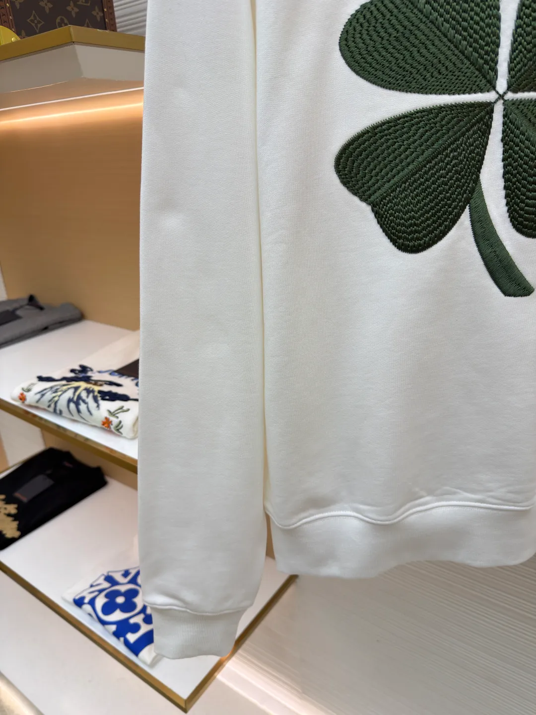 Dior four-leaf clover round neck sweatshirt ●Original version: purchased and developed by 19189 ●Item number: 1682447-A55 ●Material: pure cotton terry bottom sweatshirt fabric ●Technology: hollow embroidery production of coarse wool yarn ●Color: white ●Version: fitted version ●Weight: about 565 grams ●Size: XS-S-M-L ●Description: It adopts a fleece fabric structure of 26-count double yarn surface + 10-count yarn bottom, with a weight of 380g/㎡; with the same weight of 21-count 1x1 rib 470g/㎡. The 26-count double yarn forms a smooth and dense outer surface, and the 10-count yarn base is precisely brushed to form a rich and uniform velvet layer, thereby simultaneously achieving a crisp and skeletal feel on the outside and a skin-friendly touch like cloud velvet on the inside. Ribbing is used on the collar, cuffs and hem. Its extremely high weight and density ensure the ultimate thickness, resilience and deformation resistance of these closing parts, and together with the body, create a full and three-dimensional silhouette. The white color highlights the pure and delicate texture of the fabric and the pile loop texture on the bottom. The Dior Clover embroidery on the front uses hollow embroidery technology of coarse wool yarn. Refers to the use of special embroidery thread that is thicker and may have a plush texture. Its function is to give the embroidery pattern a unique fluffy, three-dimensional and soft touch, imitating the effect of wool weaving or tufting. This is an embroidery technique that uses specific stitches to make embroidery threads form an annular or hoop-like structure on the surface of the fabric. The embroidery thread does not adhere closely to the fabric, but forms tiny air circles, creating an extremely full, three-dimensional and elastic embroidery surface. The combination of the two creates a four-leaf clover pattern that is visually eye-catching, tactilely fluffy, and extremely handmade and artistic, forming a sharp and interesting contrast with the smooth white suede. The overall wiring is straight and delicate, the fabric is comfortable and soft, and the color is consistent without color difference. It can be matched with the same style to create a fashionable look and control various occasions. Customized accessories, complete with three standards, same style for men and women!