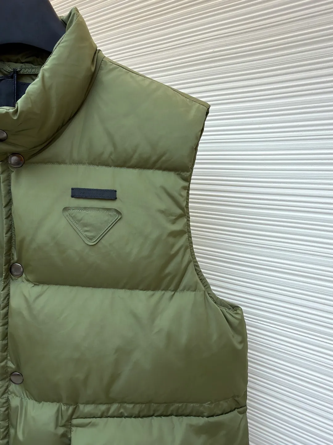 PRADA fabric triangle down vest ●Original version: Purchased and developed by 11909 ●Item number: 1681118-C10 ●Fabric: white duck down fabric ●Technology: patch production ●Version: fitted version ●Weight: about 430 grams ●Size: 46-48-50-52 ●Description: The brand's iconic regenerated nylon fabric is selected, which has the same performance as traditional nylon, with high strength, tear resistance, wear resistance and other characteristics. It is lightweight and waterproof, suitable for various scenarios. Anti-wrinkle, quick-drying and easy to maintain on a daily basis. The felt cloth material is flatly fixed on the stamping machine table. Under the control of the ground controller, the upper mold is driven to move downward at extremely high speed and pressure. The sharp edge under pressure cuts off the felt cloth fibers instantly and cleanly like a paper knife. The whole process is completed within milliseconds. Through precise calculation, the triangle shape with no burrs and brushed edges is formed. It uses 90 white duck down with a weight of 160g to ensure excellent thermal insulation performance. After strict screening and processing, the velvet is not easy to drill, ensuring durability. The overall wiring is straight and delicate, the fabric is comfortable and soft, and the color is consistent without color difference. It can be matched with the same style to create a fashionable look and control various occasions. Customized accessories, complete with three standards, same style for men and women!