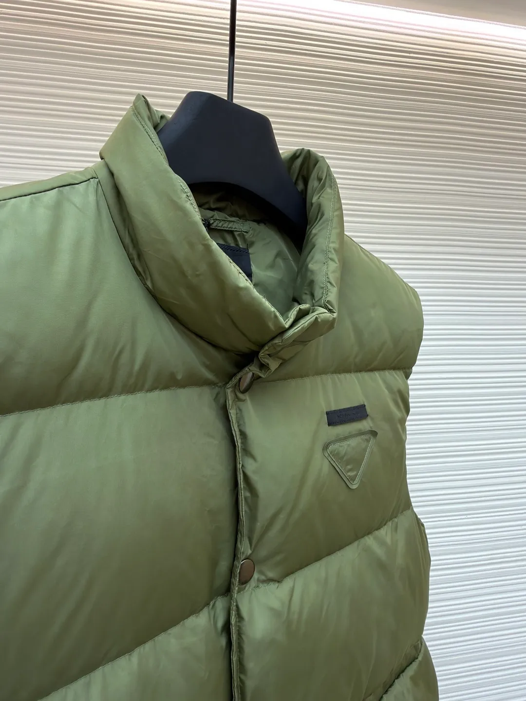 PRADA fabric triangle down vest ●Original version: Purchased and developed by 11909 ●Item number: 1681118-C10 ●Fabric: white duck down fabric ●Technology: patch production ●Version: fitted version ●Weight: about 430 grams ●Size: 46-48-50-52 ●Description: The brand's iconic regenerated nylon fabric is selected, which has the same performance as traditional nylon, with high strength, tear resistance, wear resistance and other characteristics. It is lightweight and waterproof, suitable for various scenarios. Anti-wrinkle, quick-drying and easy to maintain on a daily basis. The felt cloth material is flatly fixed on the stamping machine table. Under the control of the ground controller, the upper mold is driven to move downward at extremely high speed and pressure. The sharp edge under pressure cuts off the felt cloth fibers instantly and cleanly like a paper knife. The whole process is completed within milliseconds. Through precise calculation, the triangle shape with no burrs and brushed edges is formed. It uses 90 white duck down with a weight of 160g to ensure excellent thermal insulation performance. After strict screening and processing, the velvet is not easy to drill, ensuring durability. The overall wiring is straight and delicate, the fabric is comfortable and soft, and the color is consistent without color difference. It can be matched with the same style to create a fashionable look and control various occasions. Customized accessories, complete with three standards, same style for men and women!