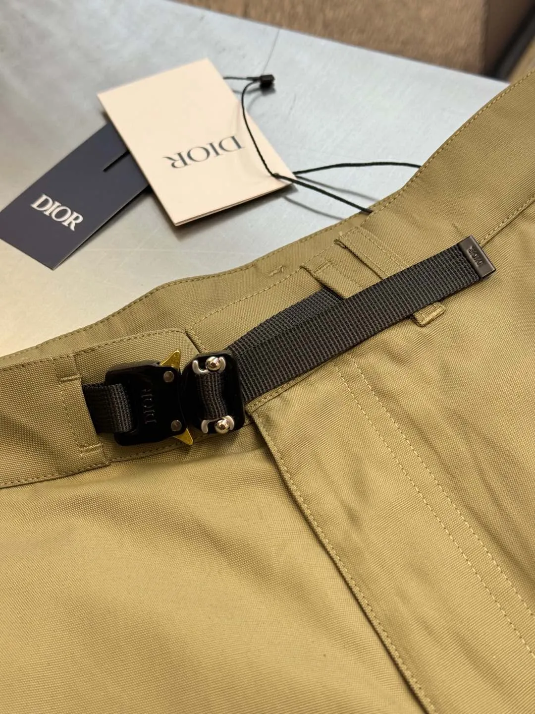 🅿️560 Dior metal buckle web trousers are made of small pique nylon fabric, customized with exclusive warp pulling on the beam to make a jacquard pan head, high-speed rapier weaving, matching 60s twill imitation Tencel cotton lining, and custom-made waistband hardware locks. The parts are hand-sprayed with glossy black paint, laser engraved with letters, side pockets with CD lettering and lacquered snap buttons, silicone stamp on the rear panel, scanned the original version and made three template corrections, 3D printed and molded in one step size: 44.46.48.50