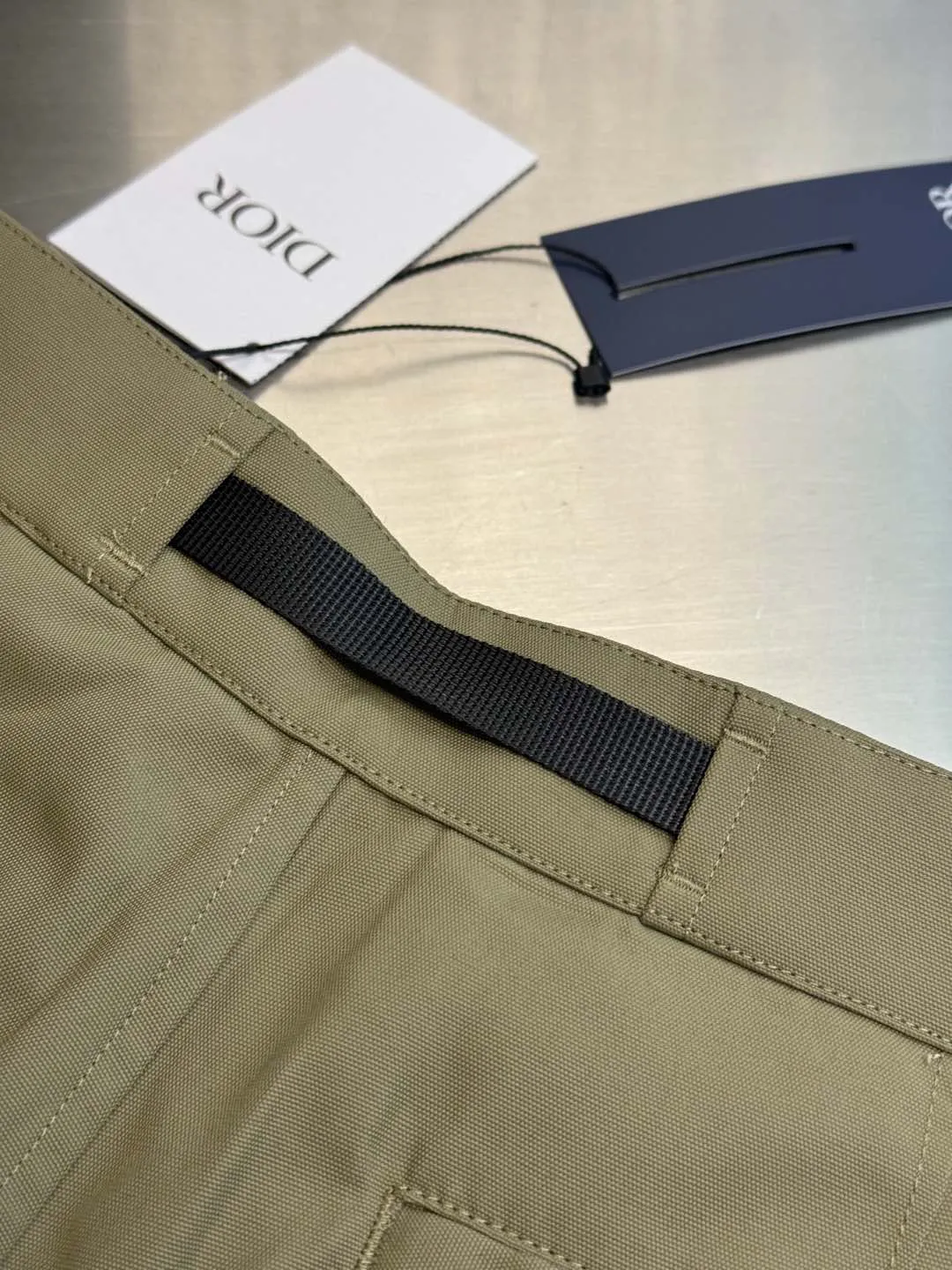 🅿️560 Dior metal buckle web trousers are made of small pique nylon fabric, customized with exclusive warp pulling on the beam to make a jacquard pan head, high-speed rapier weaving, matching 60s twill imitation Tencel cotton lining, and custom-made waistband hardware locks. The parts are hand-sprayed with glossy black paint, laser engraved with letters, side pockets with CD lettering and lacquered snap buttons, silicone stamp on the rear panel, scanned the original version and made three template corrections, 3D printed and molded in one step size: 44.46.48.50