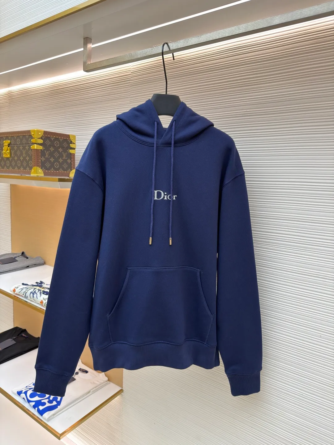 Dior classic logo embroidered hooded sweatshirt ●Item number: 1682333-A75 ●Material: cotton fabric ●Technology: embroidery production ●Color: navy blue ●Version: fitted version ●Weight: about 730 grams ●Size: XS-S-M-L ●Description: It adopts a fleece fabric structure of 26 counts of double yarn + 10S plush bottom, with a weight of 380g/㎡, and 21 counts of 1x1 ribs with a weight of 470g/㎡. It is used for the cuffs and hem. Its extremely high weight ensures the ultimate thickness, stiffness and deformation resistance of these closing parts, forming a unified and strong outline with the body. The fabric is a heavyweight and high-quality sweatshirt fabric. The 26-count double yarn forms a smooth, delicate and strong outer surface of the fabric, ensuring good color fastness and appearance. The 10S plush base undergoes a precise fleece or brushing process to form a layer of rich, dense and uniform fluff on the inside of the fabric. This makes the sweatshirt have a crisp and skeletal feel on the outside and an extremely soft and warm feel on the inside. White tone twill needle embroidery process. Needle embroidery is a straight line embroidery with stitches closely connected and evenly arranged. It is often used to outline clear and sharp outlines. This stitch is used to embroider a diagonal stripe pattern with a certain angle and width. Use white embroidery thread to follow the preset diagonal trajectory and perform precise embroidery with high-density stitches. On the high-weight fabric base, simple, exquisite and three-dimensional line decoration is created. The contrast between white and fabric color is sharp, and the slightly convex texture brought by the embroidery adds a visual and tactile layer, effectively enhancing the exquisite style of the basic sweatshirt. The overall wiring is straight and delicate, the fabric is comfortable and soft, and the color is consistent without color difference. It can be matched with the same style to create a fashionable look and control various occasions. Customized accessories, complete with three standards, same style for men and women!
