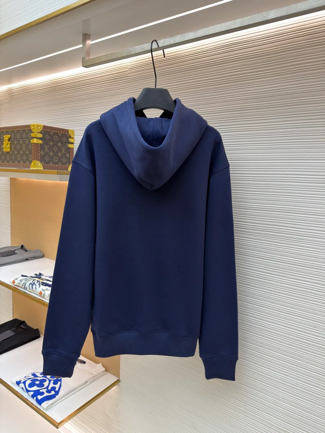 Dior classic logo embroidered hooded sweatshirt ●Item number: 1682333-A75 ●Material: cotton fabric ●Technology: embroidery production ●Color: navy blue ●Version: fitted version ●Weight: about 730 grams ●Size: XS-S-M-L ●Description: It adopts a fleece fabric structure of 26 counts of double yarn + 10S plush bottom, with a weight of 380g/㎡, and 21 counts of 1x1 ribs with a weight of 470g/㎡. It is used for the cuffs and hem. Its extremely high weight ensures the ultimate thickness, stiffness and deformation resistance of these closing parts, forming a unified and strong outline with the body. The fabric is a heavyweight and high-quality sweatshirt fabric. The 26-count double yarn forms a smooth, delicate and strong outer surface of the fabric, ensuring good color fastness and appearance. The 10S plush base undergoes a precise fleece or brushing process to form a layer of rich, dense and uniform fluff on the inside of the fabric. This makes the sweatshirt have a crisp and skeletal feel on the outside and an extremely soft and warm feel on the inside. White tone twill needle embroidery process. Needle embroidery is a straight line embroidery with stitches closely connected and evenly arranged. It is often used to outline clear and sharp outlines. This stitch is used to embroider a diagonal stripe pattern with a certain angle and width. Use white embroidery thread to follow the preset diagonal trajectory and perform precise embroidery with high-density stitches. On the high-weight fabric base, simple, exquisite and three-dimensional line decoration is created. The contrast between white and fabric color is sharp, and the slightly convex texture brought by the embroidery adds a visual and tactile layer, effectively enhancing the exquisite style of the basic sweatshirt. The overall wiring is straight and delicate, the fabric is comfortable and soft, and the color is consistent without color difference. It can be matched with the same style to create a fashionable look and control various occasions. Customized accessories, complete with three standards, same style for men and women!