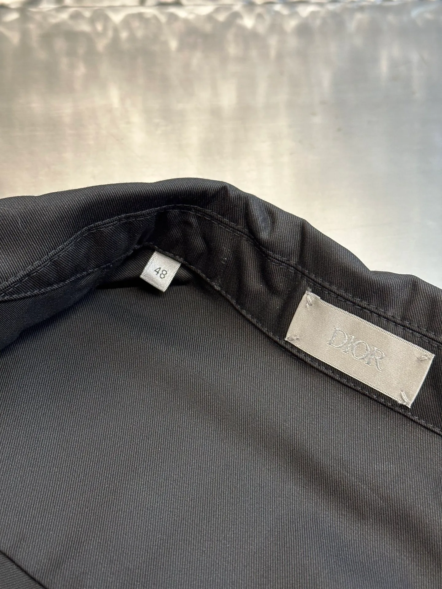 🅿️650 DIOR CD icon embroidered jacket is made of black gabardine fabric, with a smooth and delicate surface, soft touch, and elegant luster. Its tight textile construction makes it resistant to wrinkles, abrasion and drape. The wool component makes it warm and breathable. Gabardine fabric is not easy to pill, has good stain resistance, and is easy to care for daily.  The modern fit has a slim fit and a hidden zip closure adds understated sophistication. High-precision sewing technology ensures a perfect fit between the zipper and the fabric. The lapel design of traditional shirts still meets the needs of formal occasions. There is a patch pocket on the chest and is decorated with CD icon embroidery, which highlights the brand's iconic elements. The bag opening also has a hidden zipper opening, and the bag opening is reinforced with pocket knotting technology at the beginning and end. Tight stitching at the edge of the bag body makes it strong and beautiful. There are side pockets on the left and right sides, and the pocket openings are only 0.5 cm hemmed, which retains the smoothness of the overall lines without losing practicality. The double-button design of traditional shirt cuffs makes the cuffs fit more closely on the wrist and prevent them from loosening.  size：s m l xl