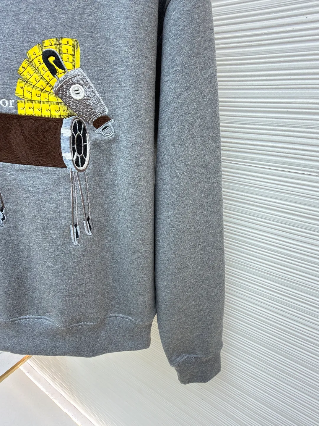Dior horse embroidery round neck sweatshirt ●Original version: purchased and developed by 13941 ●Item number: 1682562-A70 ●Fabric: cotton fleece fabric ●Technology: embroidery production ●Color: gray ●Version: fitted version ●Weight: about 590 grams ●Size: XS-S-M-L ●Description: This product adopts a terry fabric structure of 26-count double yarn surface + 10-count yarn base, with a weight of 380g/㎡; the matching 21-count 1x1 rib also weighs 470g/㎡, and is used for the collar, cuffs and hem, and is a heavyweight sweatshirt fabric. The 26-count double yarn forms a smooth and delicate outer surface of the fabric, ensuring good color fastness. The 10-count yarn base is precision brushed to form a layer of rich, dense skin-friendly velvet on the inside of the fabric, providing excellent warmth and soft wrapping. The extremely high weight of the rib ensures the ultimate thickness, stiffness and deformation resistance of these closing parts; together with the body, it builds a full three-dimensional silhouette, and the gray color highlights the texture and high-end sense of the fabric. Environmentally friendly elastic glue printing: Printing the background of the pony pattern. This printing process is characterized by bright colors, strong coverage, and the elastic glue can stretch with the fabric without cracking, and the touch is relatively soft. Its function is to provide a large-area, flat color base and design framework for the entire pattern. Needle embroidery achieves three-dimensional reshaping of the pattern by superimposing high-density straight stitches on the printing base. It uses multi-color embroidery thread at an extreme density to continuously fill the outline and structure, accurately shaping the image and completing the color transition by changing threads. The overall wiring is straight and delicate, the fabric is comfortable and soft, and the color is consistent without color difference. It can be matched with the same style to create a fashionable look and control various occasions. Customized accessories, complete with three standards, same style for men and women!