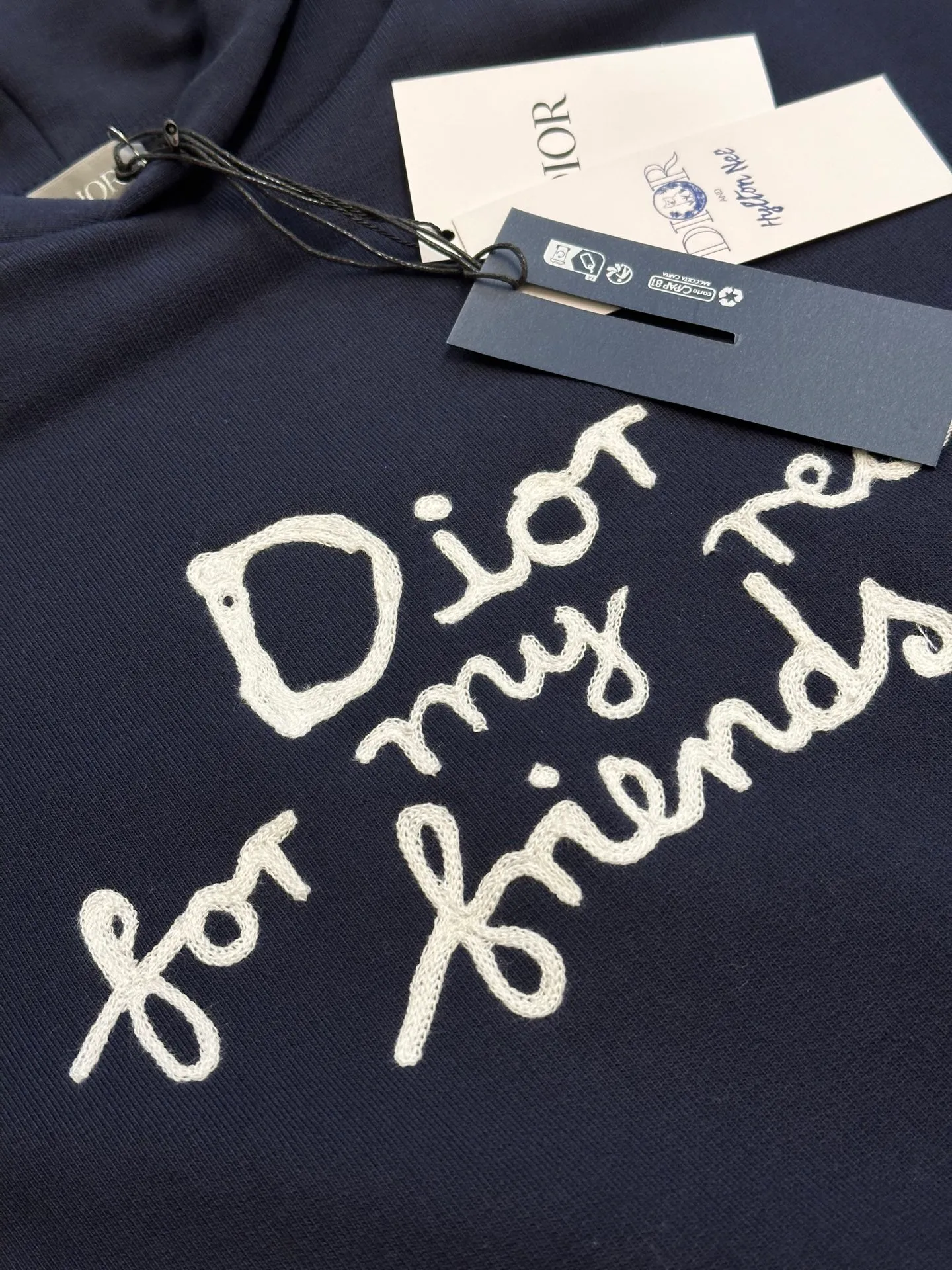 🅿️500 Dior Friends letter embroidered hooded sweatshirt. Cotton fleece fish scale bottom fabric. The surface of the 32-count double-yarn woven fabric is fine and tight, and it feels soft and comfortable. The weight of 50g and the bottom design of 10-count yarn make the fabric have good warmth retention and durability. Thanks to the relatively fine yarns used, this sweatshirt fabric is soft to the touch and comfortable to wear. The design of the fish scale base also increases the skin-friendliness of the fabric, making the wearing experience better. This fabric maintains softness while also possessing good wear-resistance and wrinkle-resistance.  The joint series logo is chain embroidery. Chain embroidery is named because the visual effect of the embroidery is like a chain. The shape is like the links on the chain. It is commonly known as chain embroidery and also called chain eye embroidery. Follow the chain stitch stitch method and embroider from right to left. Maintain the tension of the embroidery thread and the uniformity of the stitches to ensure the three-dimensionality and exquisiteness of the embroidery. It combines the stitching method of chain embroidery with the material of fine wool to create embroidery with chain-like texture and three-dimensional effect.  The hooded drop-shoulder is a loose fit, because it is quite loosely cut, and the shoulder line is large. The drop-shoulder design has no limit on shoulder width. The hem and cuffs are spliced ​​with ribs, which can provide wind protection; the hooded sweatshirt maintains a certain degree of looseness while maintaining a slim fit. The length of the sweatshirt is moderate, which can show the curves of the figure and present an elegant and fashionable feeling.  size：xs s m l