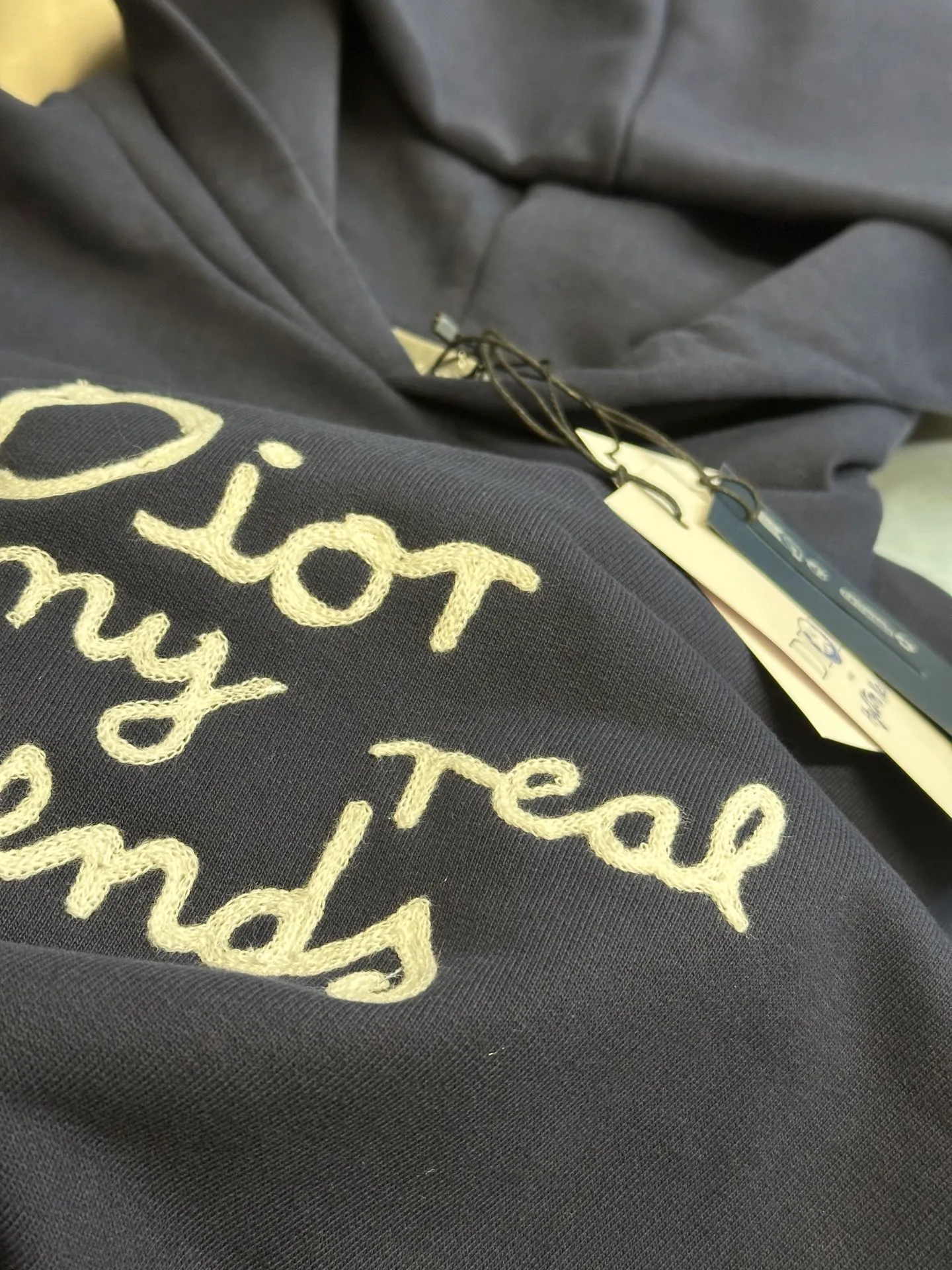 🅿️500 Dior Friends letter embroidered hooded sweatshirt. Cotton fleece fish scale bottom fabric. The surface of the 32-count double-yarn woven fabric is fine and tight, and it feels soft and comfortable. The weight of 50g and the bottom design of 10-count yarn make the fabric have good warmth retention and durability. Thanks to the relatively fine yarns used, this sweatshirt fabric is soft to the touch and comfortable to wear. The design of the fish scale base also increases the skin-friendliness of the fabric, making the wearing experience better. This fabric maintains softness while also possessing good wear-resistance and wrinkle-resistance.  The joint series logo is chain embroidery. Chain embroidery is named because the visual effect of the embroidery is like a chain. The shape is like the links on the chain. It is commonly known as chain embroidery and also called chain eye embroidery. Follow the chain stitch stitch method and embroider from right to left. Maintain the tension of the embroidery thread and the uniformity of the stitches to ensure the three-dimensionality and exquisiteness of the embroidery. It combines the stitching method of chain embroidery with the material of fine wool to create embroidery with chain-like texture and three-dimensional effect.  The hooded drop-shoulder is a loose fit, because it is quite loosely cut, and the shoulder line is large. The drop-shoulder design has no limit on shoulder width. The hem and cuffs are spliced ​​with ribs, which can provide wind protection; the hooded sweatshirt maintains a certain degree of looseness while maintaining a slim fit. The length of the sweatshirt is moderate, which can show the curves of the figure and present an elegant and fashionable feeling.  size：xs s m l
