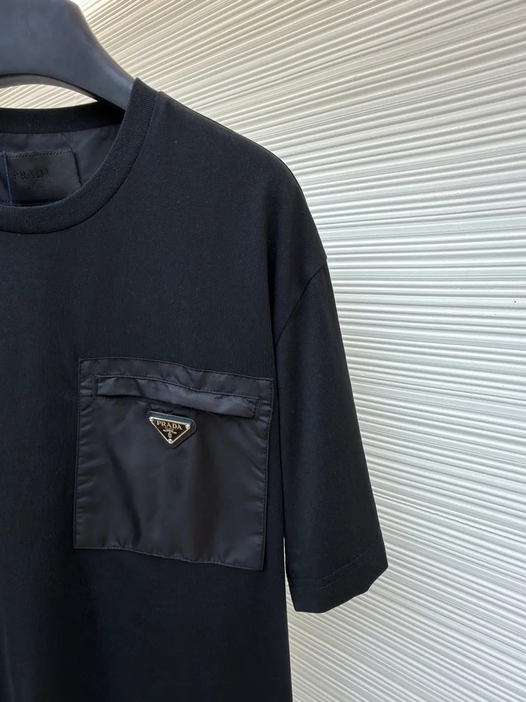 Prada Triangle Logo Pocket Short Sleeves ●Original version: Purchased and developed for 7000 ●Item number: 1682396-A05 ●Fabric: High-elastic jersey fabric ●Technology: Needle and shuttle stitching ●Color: black ●Version: Fitted version ●Weight: about 235 grams ●Size: S-M-L-XL ●Description: Customized high-elastic jersey material, delicate and soft, comfortable and close to the skin, a touch of simple white, pure and elegant. The iconic Prada triangle logo is embellished on the chest. It is integrated with Re-Nylon nylon fabric to decorate the square silhouette. Cross-disciplinary aesthetic grafting. The exquisite small pocket design highlights quality and style. It reveals a flexible and relaxed beauty. It is a picture of strolling in the city and deconstructs the attitude of the modern gentleman. The infrared positioning of the "Prada triangle mark" by an imported special machine is more precise and firm. Needle and shuttle stitching technology can make full use of the respective advantages of knitted fabrics and woven fabrics. By choosing the appropriate sewing process and stitches, it can ensure that the splicing parts are strong and beautiful. Template machine bag opening The preset template guides the position, shape and size of the bag opening. The accuracy ensures the quality of the bag opening effect. The overall wiring is straight and delicate, the fabric is comfortable and soft, and the color is consistent without color difference. It can be matched with the same style to create a fashionable look and control various occasions. Customized accessories, complete with three standards, same style for men and women!