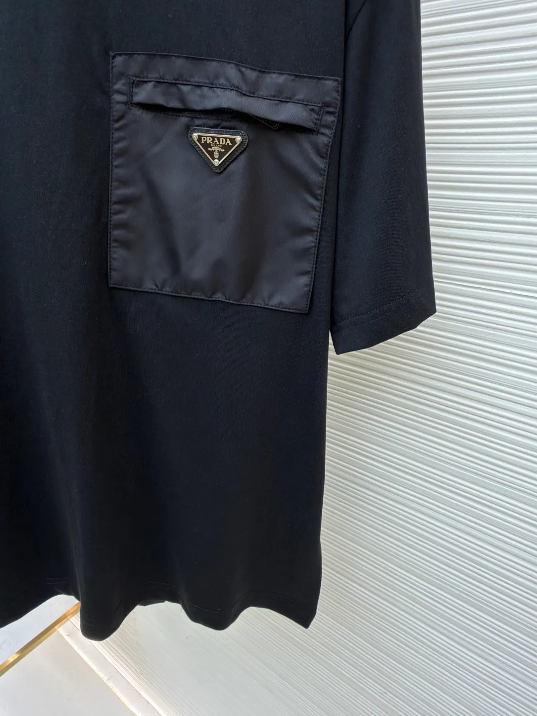 Prada Triangle Logo Pocket Short Sleeves ●Original version: Purchased and developed for 7000 ●Item number: 1682396-A05 ●Fabric: High-elastic jersey fabric ●Technology: Needle and shuttle stitching ●Color: black ●Version: Fitted version ●Weight: about 235 grams ●Size: S-M-L-XL ●Description: Customized high-elastic jersey material, delicate and soft, comfortable and close to the skin, a touch of simple white, pure and elegant. The iconic Prada triangle logo is embellished on the chest. It is integrated with Re-Nylon nylon fabric to decorate the square silhouette. Cross-disciplinary aesthetic grafting. The exquisite small pocket design highlights quality and style. It reveals a flexible and relaxed beauty. It is a picture of strolling in the city and deconstructs the attitude of the modern gentleman. The infrared positioning of the "Prada triangle mark" by an imported special machine is more precise and firm. Needle and shuttle stitching technology can make full use of the respective advantages of knitted fabrics and woven fabrics. By choosing the appropriate sewing process and stitches, it can ensure that the splicing parts are strong and beautiful. Template machine bag opening The preset template guides the position, shape and size of the bag opening. The accuracy ensures the quality of the bag opening effect. The overall wiring is straight and delicate, the fabric is comfortable and soft, and the color is consistent without color difference. It can be matched with the same style to create a fashionable look and control various occasions. Customized accessories, complete with three standards, same style for men and women!