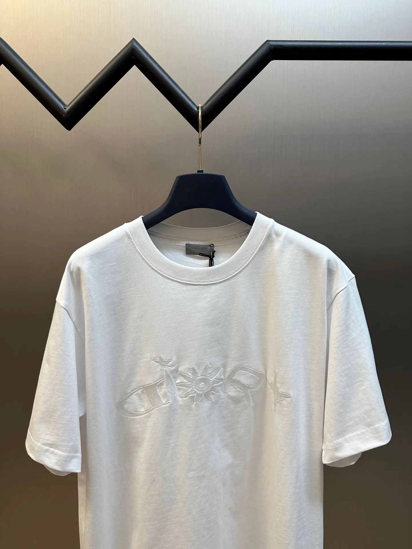 🅿️260 Dior co-branded embroidered round neck short-sleeved cotton jersey fabric, made of 15S fine cotton plain weave, 230g; paired with threaded 32S double yarn rack, 300g. 15S is a relatively thick yarn used to make thicker and more durable fabrics. The fabric made of pure cotton natural fiber has the characteristics of good hygroscopicity, strong breathability, softness and comfort. Cotton fabrics are generally suitable for summer wear and can help keep your body dry and comfortable. The yarn passes alternately in the horizontal and vertical directions to form a simple cross structure; it has good elasticity and wear resistance.  It is processed by needle embroidery process, and the main body adopts precision needle embroidery process; the embroidery is very fine and dense, the pattern is clear and the lines and three-dimensional sense are strong. The linen material embroidery thread is combined with encrypted processing, and the embroidery body has a subtle matte visual texture; the embroidery effect is three-dimensional and full. The flat embroidery has a unique needle-to-needle design, and the embroidery is very fine and dense. The overall stitching is fine, with consistent fineness and texture, adding a sense of layering to the simple design.  The standard round neck and short-sleeved version has a rounded arc neckline, which is suitable for various face shapes and body shapes; the sleeve length is moderate and ends just above the elbow, showing a smart and neat image. The slim fit can show off the wearer's body curves without sacrificing comfort. The collar, cuffs, hem and other parts are all sewn with fine double-needle stitching.  size：xs s m l