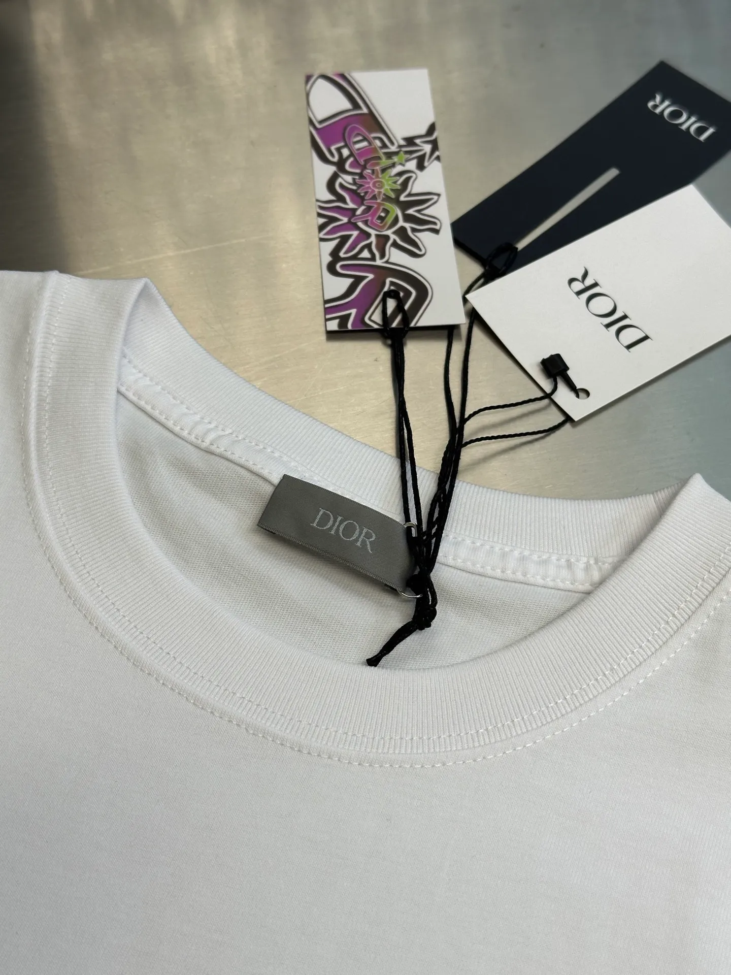 🅿️260 Dior co-branded embroidered round neck short-sleeved cotton jersey fabric, made of 15S fine cotton plain weave, 230g; paired with threaded 32S double yarn rack, 300g. 15S is a relatively thick yarn used to make thicker and more durable fabrics. The fabric made of pure cotton natural fiber has the characteristics of good hygroscopicity, strong breathability, softness and comfort. Cotton fabrics are generally suitable for summer wear and can help keep your body dry and comfortable. The yarn passes alternately in the horizontal and vertical directions to form a simple cross structure; it has good elasticity and wear resistance.  It is processed by needle embroidery process, and the main body adopts precision needle embroidery process; the embroidery is very fine and dense, the pattern is clear and the lines and three-dimensional sense are strong. The linen material embroidery thread is combined with encrypted processing, and the embroidery body has a subtle matte visual texture; the embroidery effect is three-dimensional and full. The flat embroidery has a unique needle-to-needle design, and the embroidery is very fine and dense. The overall stitching is fine, with consistent fineness and texture, adding a sense of layering to the simple design.  The standard round neck and short-sleeved version has a rounded arc neckline, which is suitable for various face shapes and body shapes; the sleeve length is moderate and ends just above the elbow, showing a smart and neat image. The slim fit can show off the wearer's body curves without sacrificing comfort. The collar, cuffs, hem and other parts are all sewn with fine double-needle stitching.  size：xs s m l
