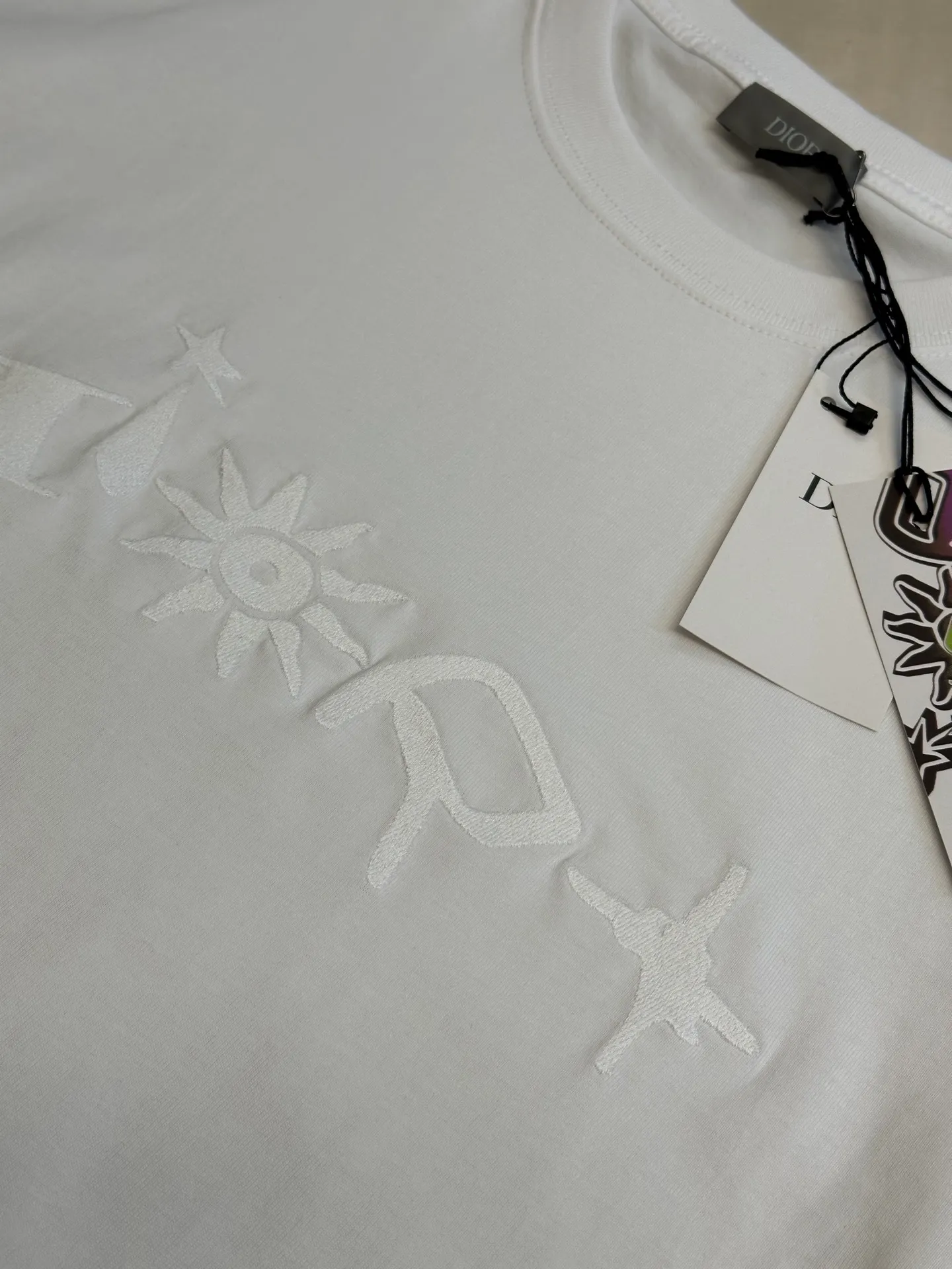 🅿️260 Dior co-branded embroidered round neck short-sleeved cotton jersey fabric, made of 15S fine cotton plain weave, 230g; paired with threaded 32S double yarn rack, 300g. 15S is a relatively thick yarn used to make thicker and more durable fabrics. The fabric made of pure cotton natural fiber has the characteristics of good hygroscopicity, strong breathability, softness and comfort. Cotton fabrics are generally suitable for summer wear and can help keep your body dry and comfortable. The yarn passes alternately in the horizontal and vertical directions to form a simple cross structure; it has good elasticity and wear resistance.  It is processed by needle embroidery process, and the main body adopts precision needle embroidery process; the embroidery is very fine and dense, the pattern is clear and the lines and three-dimensional sense are strong. The linen material embroidery thread is combined with encrypted processing, and the embroidery body has a subtle matte visual texture; the embroidery effect is three-dimensional and full. The flat embroidery has a unique needle-to-needle design, and the embroidery is very fine and dense. The overall stitching is fine, with consistent fineness and texture, adding a sense of layering to the simple design.  The standard round neck and short-sleeved version has a rounded arc neckline, which is suitable for various face shapes and body shapes; the sleeve length is moderate and ends just above the elbow, showing a smart and neat image. The slim fit can show off the wearer's body curves without sacrificing comfort. The collar, cuffs, hem and other parts are all sewn with fine double-needle stitching.  size：xs s m l