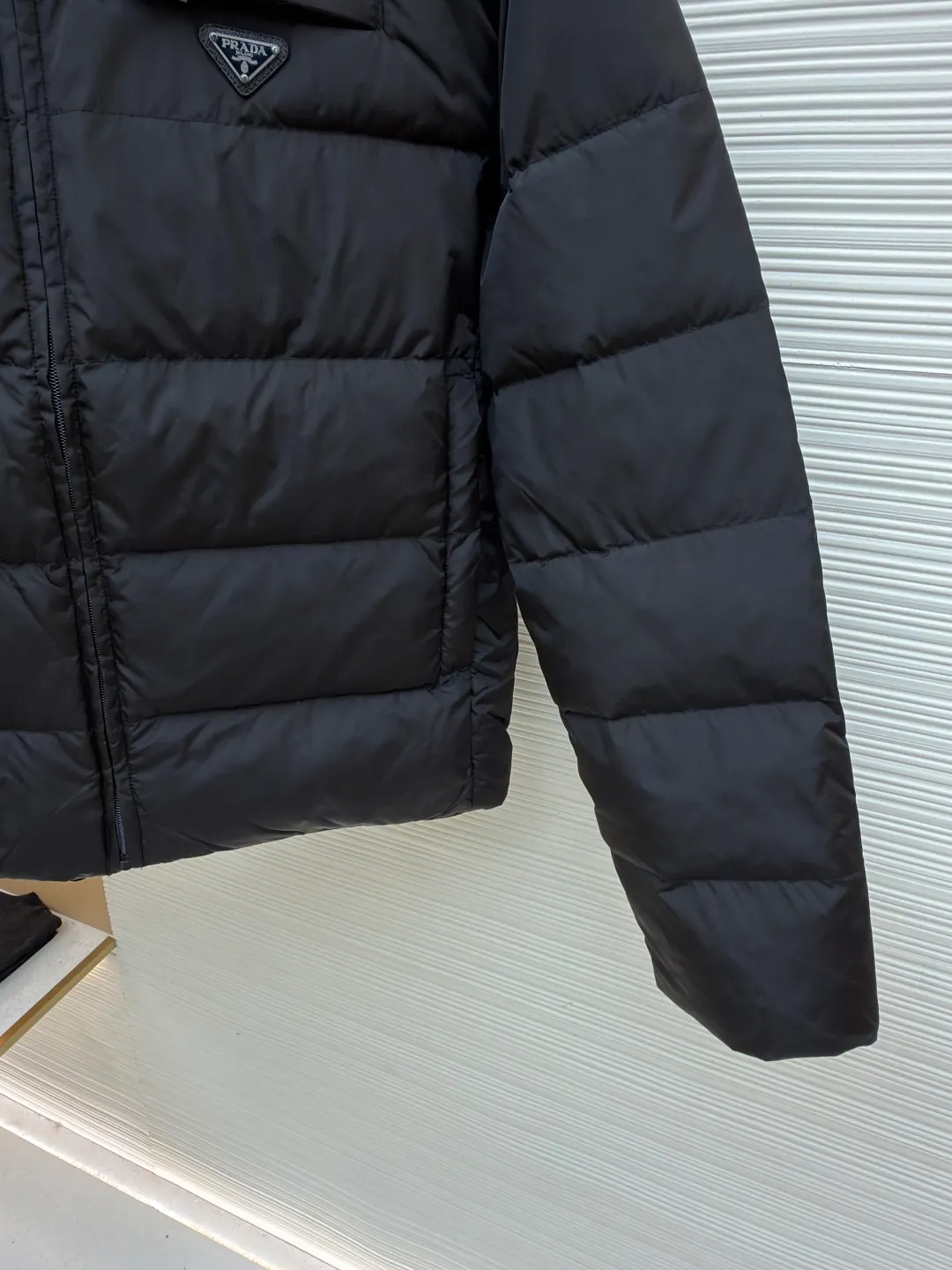 Prada triangle pocket down jacket ●Original version: Purchased and developed in 19800 ●Item number: 1681902-D20 ●Fabric: white duck down fabric ●Technology: mechanical down filling ●Color: black ●Version: fitted version ●Weight: about 675 grams ●Size: 46-48-50-52 ●Description: Customized ultra-dense round hole woven fabric (with anti-repellent treatment) showing a matte micro-texture Use the new national standard 90 white duck down (welcome to test), full of down, full of warmth, you are in a warm cloud, surrounded by soft warmth, the classic black tone exudes an innate sense of luxury, the iconic enameled metal triangle logo is embellished on the chest, low-key and powerful, the stand-up collar is crisp and stylish, accurately fits the neck curve, and uses architectural lines to reconstruct the warmth and neatness of the bloated down jacket. Enjoy warmth and comfort. Become the most considerate companion for mechanical down filling in winter. Prioritize the filling area by making the liner pattern to determine the gram weight of down per square meter according to the original three-dimensional effect, thereby calculating the filling amount of each piece. The computer down filling machine uses a digital weighing unit to achieve stable measurement, and uses imported special machine infrared to locate the "Prada triangle mark" for more accurate positioning. The firm and strong template machine opens the zipper bag. The lines are smooth and tidy. The wiring is even and the template machine lines the lines. The line process of the computer template machine shows extremely high neatness and smoothness. The craftsman accurately controls the size during the operation to ensure that each line meets the design requirements. The lines of the entire template are smooth and uniform, clean and beautiful. The overall wiring is straight and delicate, the fabric is comfortable and soft, and the color is consistent without color difference. It can be matched with the same style to create a fashionable look and control various occasions. Customized accessories, complete with three standards, same style for men and women!