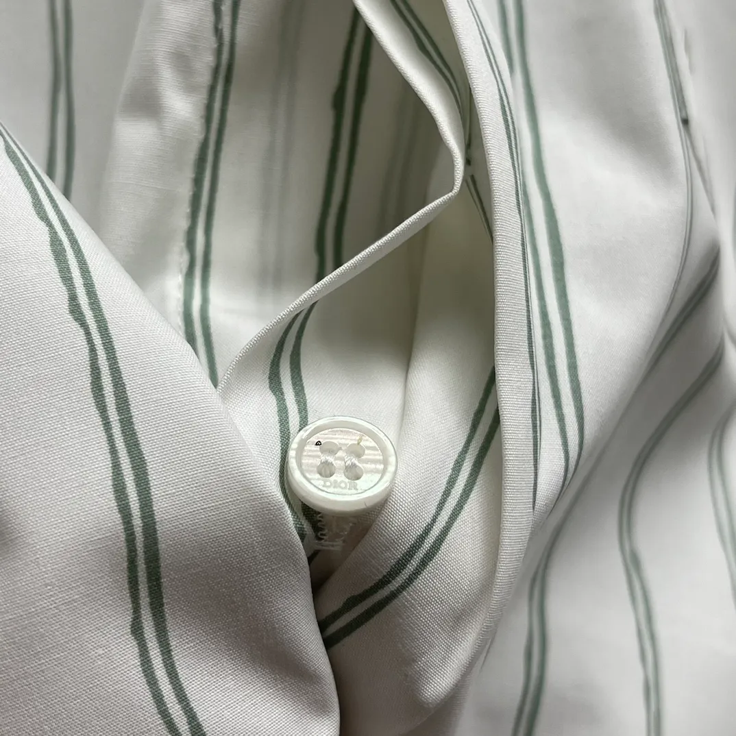 🅿️480 CD Blue and gray vertical pattern simple embroidered shirt Size: S-XL This shirt combines modern style with traditional beauty. Crafted from white cotton poplin, it features a blue and gray striped pattern displaying the Dior For My Real Friends signature from the DIOR AND HYLTON NE collection. A patch pocket on the chest and hidden button closure complete the design. Can be worn with everyday clothing.