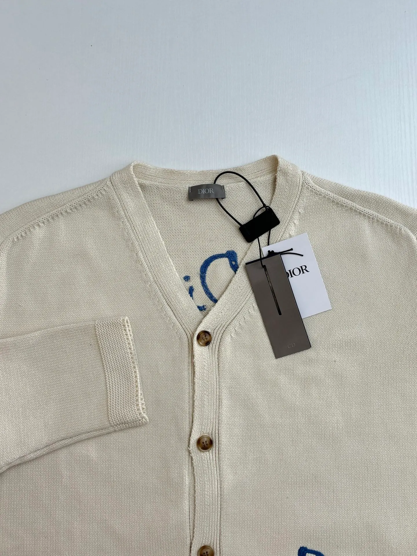 🅿️500 Dio*/Dior 25Fw new friend embroidered cotton blend button cardigan. The fabric is made of 40-count cotton yarn and wool, and the cotton content is 62%. It is mixed with 38% polyester. Mixing two kinds of wool materials can effectively make the upper body more three-dimensional. The embroidery uses high-density wool yarn embroidery technology, and the front numbers are all equipped with the joint series embroidery LOGO. The number of stitches is about 12,000. The auxiliary buttons are made of natural horn buttons, with the brand's iconic [DIOR] LOGO on the buttons. This cardigan displays the Dior For My Real Friends logo from the DIOR AND HYLTON NEL collaboration. Crafted from white cotton-blend jersey with embroidery on the front and back, button fastening and ribbed trims.  Size：S/M/L