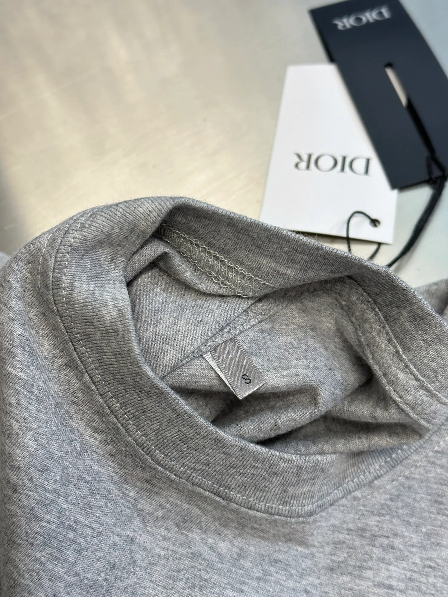 🅿️260 Dior Love Series Pocket Embroidery Round Neck Short Sleeve Cotton Jersey Fabric. Made of 24S special woven compact cotton fabric, 185g; with 32S double yarn thread, 300g. The strength of compact yarn is higher than that of traditional single yarn. The single fibers in compact yarn are closely arranged, which helps to improve the strength of the yarn. The ends of the fibers are all twisted into the yarn, so the yarn is very tight and the yarn has a smooth appearance with less hairiness. Compact spinning yarn has higher strength and less hairiness, making it less prone to fraying.  The chest is decorated with embroidery patterns, and the main body adopts precision stitch embroidery technology; the embroidery is very fine and dense, with clear patterns and strong lines and three-dimensionality. The linen material embroidery thread is combined with encrypted processing, and the embroidery body has a subtle matte visual texture; the embroidery effect is three-dimensional and full. The flat embroidery has a unique needle-to-needle design, and the embroidery is very fine and dense. The overall stitching is fine, with consistent fineness and texture, adding a sense of layering to the simple design.  Standard crew neck, short sleeve fit. The neckline is rounded and arc-shaped, suitable for various face shapes and body shapes; the sleeve length is moderate and ends just above the elbow, showing a smart and neat image. The slim fit can show off the wearer's body curves without sacrificing comfort. The collar, cuffs, hem and other parts are all sewn with fine double-needle stitching.  size：xs s m l