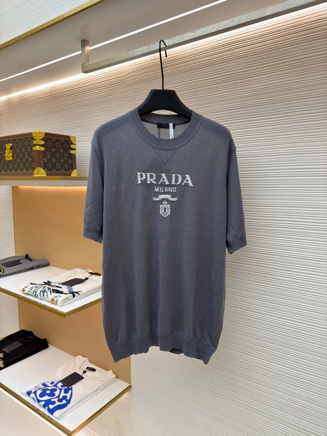 Prada classic LOGO jacquard wool round neck short sleeves ●Original version: purchased and developed by 11988 ●Item number: 1682515-A45 ●Fabric: wool fabric ●Technology: jacquard production ●Color: gray ●Version: fitted version ●Weight: about 150 grams ●Size: 46-48-50-52 ●Description: This PRADA gray knitted short-sleeve is woven with high-quality combed cotton threads. The body is made of vertical pit knitting technology. The texture is three-dimensional and elastic. It is soft and breathable when worn next to the skin. It has good drape and stiffness, and is not prone to pilling and deformation. The brand letters and badge pattern on the front of the garment are made with precision embroidery technology. The embroidery thread is made of imported high-gloss yarn. The stitches are dense and even, and the pattern is three-dimensional and clear. It forms a texture contrast with the knitted base to highlight the brand recognition. The neckline is a classic round neck design, with double-needle reinforced hemming technology and a customized threaded collar, which is durable and not easy to loosen. The cuffs and hem are ribbed in the same color. The overall cut is a loose silhouette. The stitching is straight and fine. The customized accessories and three standards are complete. The detailed craftsmanship shows the level of luxury. It is suitable for casual daily and light business wear scenarios. The overall wiring is straight and delicate, the fabric is comfortable and soft, and the color is consistent without color difference. It can be matched with the same style to create a fashionable look and control various occasions. Customized accessories, complete with three standards, same style for men and women!