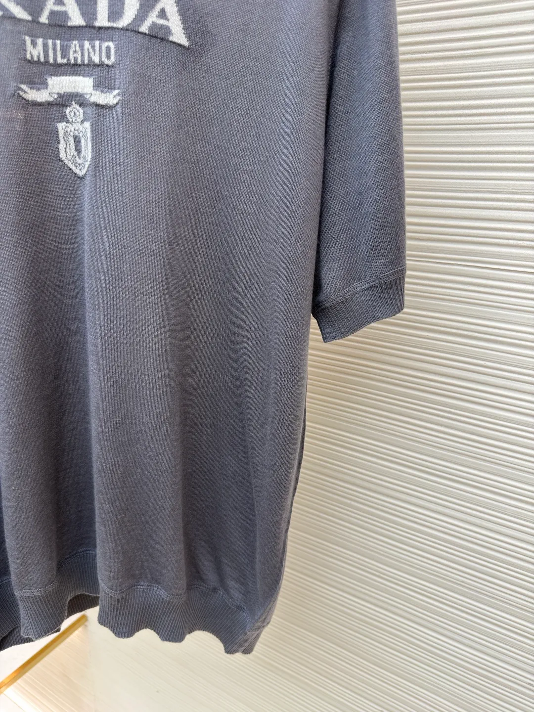 Prada classic LOGO jacquard wool round neck short sleeves ●Original version: purchased and developed by 11988 ●Item number: 1682515-A45 ●Fabric: wool fabric ●Technology: jacquard production ●Color: gray ●Version: fitted version ●Weight: about 150 grams ●Size: 46-48-50-52 ●Description: This PRADA gray knitted short-sleeve is woven with high-quality combed cotton threads. The body is made of vertical pit knitting technology. The texture is three-dimensional and elastic. It is soft and breathable when worn next to the skin. It has good drape and stiffness, and is not prone to pilling and deformation. The brand letters and badge pattern on the front of the garment are made with precision embroidery technology. The embroidery thread is made of imported high-gloss yarn. The stitches are dense and even, and the pattern is three-dimensional and clear. It forms a texture contrast with the knitted base to highlight the brand recognition. The neckline is a classic round neck design, with double-needle reinforced hemming technology and a customized threaded collar, which is durable and not easy to loosen. The cuffs and hem are ribbed in the same color. The overall cut is a loose silhouette. The stitching is straight and fine. The customized accessories and three standards are complete. The detailed craftsmanship shows the level of luxury. It is suitable for casual daily and light business wear scenarios. The overall wiring is straight and delicate, the fabric is comfortable and soft, and the color is consistent without color difference. It can be matched with the same style to create a fashionable look and control various occasions. Customized accessories, complete with three standards, same style for men and women!