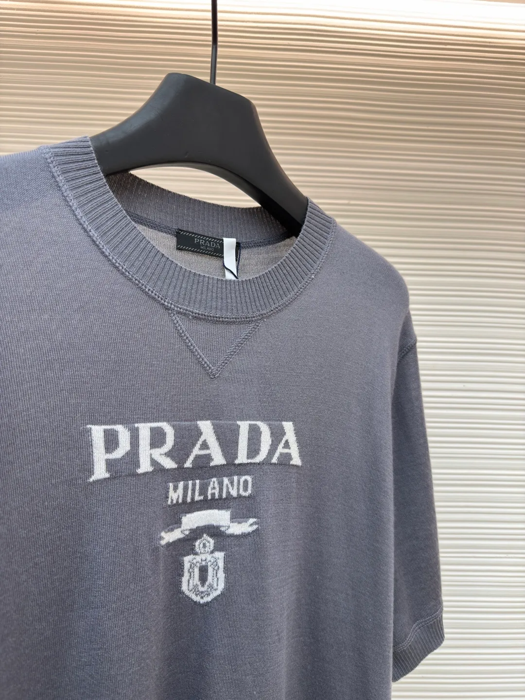 Prada classic LOGO jacquard wool round neck short sleeves ●Original version: purchased and developed by 11988 ●Item number: 1682515-A45 ●Fabric: wool fabric ●Technology: jacquard production ●Color: gray ●Version: fitted version ●Weight: about 150 grams ●Size: 46-48-50-52 ●Description: This PRADA gray knitted short-sleeve is woven with high-quality combed cotton threads. The body is made of vertical pit knitting technology. The texture is three-dimensional and elastic. It is soft and breathable when worn next to the skin. It has good drape and stiffness, and is not prone to pilling and deformation. The brand letters and badge pattern on the front of the garment are made with precision embroidery technology. The embroidery thread is made of imported high-gloss yarn. The stitches are dense and even, and the pattern is three-dimensional and clear. It forms a texture contrast with the knitted base to highlight the brand recognition. The neckline is a classic round neck design, with double-needle reinforced hemming technology and a customized threaded collar, which is durable and not easy to loosen. The cuffs and hem are ribbed in the same color. The overall cut is a loose silhouette. The stitching is straight and fine. The customized accessories and three standards are complete. The detailed craftsmanship shows the level of luxury. It is suitable for casual daily and light business wear scenarios. The overall wiring is straight and delicate, the fabric is comfortable and soft, and the color is consistent without color difference. It can be matched with the same style to create a fashionable look and control various occasions. Customized accessories, complete with three standards, same style for men and women!