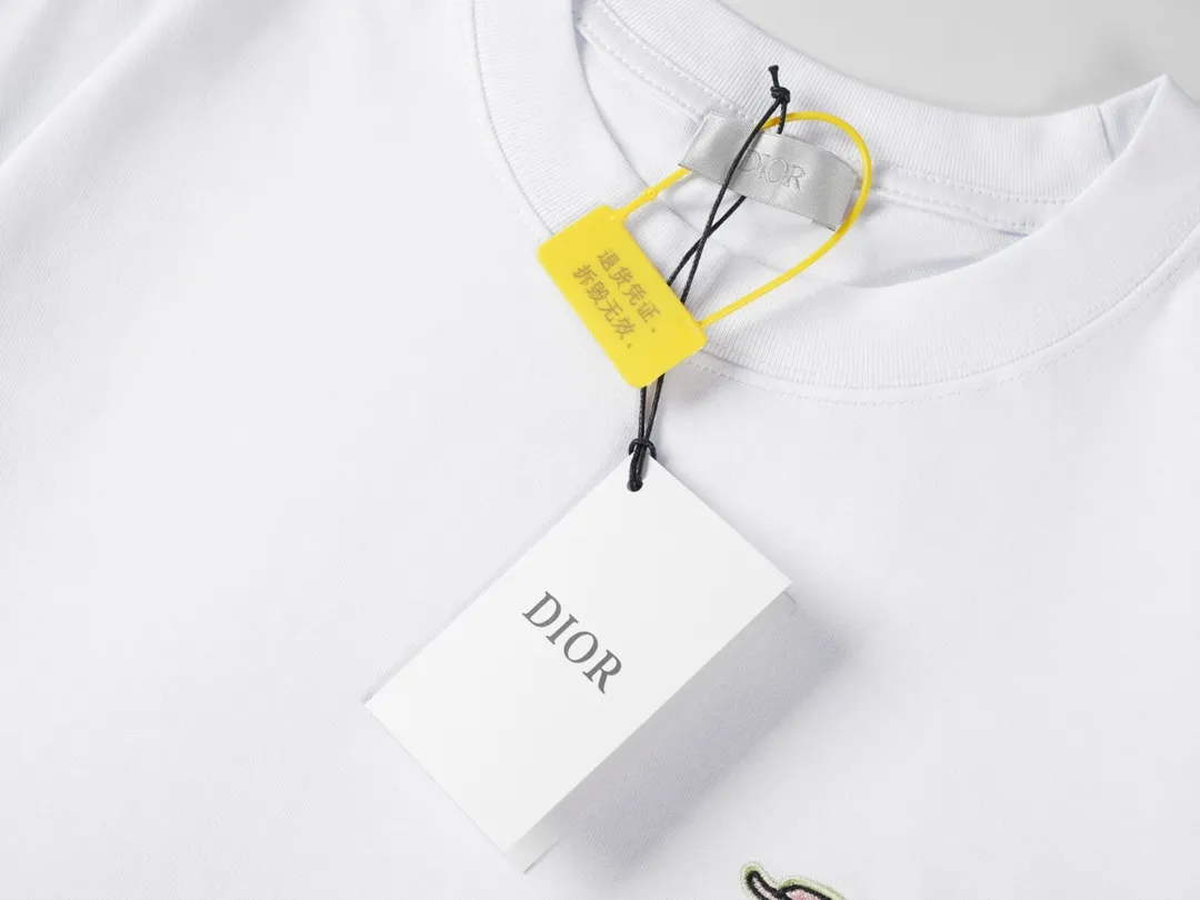 🅿️190 CD 2025 new style embroidered letter short sleeves. This T-shirt is from the DO AND KAWS limited series. Crafted from cotton jersey and embellished with DO AND KAWS embroidery, the Do logo is reinterpreted as a colorful snake. Wear it with the limited edition trousers for a refined look.  Cotton jersey fabric is a knitted fabric made of cotton fiber. The fabric has good moisture absorption and breathability. The softness and skin-friendly nature of the cotton fiber make the fabric feel comfortable to the touch. The fabric structure gives the fabric a certain degree of strength and stability, but its elasticity may be less than other complex weaving methods.  The tatami mat serves as the base for embroidery, ensuring its surface is flat and suitable for embroidery. The stitches of the embroidery are very tight, which makes the surface of the embroidery pattern smooth and delicate, and feels smooth to the touch. The use of bright silk threads for embroidery makes the pattern rich and full in color and has a strong visual impact.  Using a backstitch stitch, embroider along the edges of the design. The embroidery keeps the stitches tight and flat, and embroiders narrow strip-like graphics to ensure that the hemming effect shows a strong sense of line and three-dimensionality. CD / KAWS loose fit T-shirt Fabric: 12S fine cotton plain fabric / 310G Rib: 21S double yarn stretcher / 420G This T-shirt is from the DO AND KAWS limited series. Crafted from cotton jersey and embellished with DO AND KAWS embroidery, the Do logo is reinterpreted as a colorful snake. Wear it with the limited edition trousers for a refined look.  Cotton jersey fabric is a knitted fabric made of cotton fiber. The fabric has good moisture absorption and breathability. The softness and skin-friendly nature of the cotton fiber make the fabric feel comfortable to the touch. The fabric structure gives the fabric a certain degree of strength and stability, but its elasticity may be less than other complex weaving methods.  The tatami mat serves as the base for embroidery, ensuring its surface is flat and suitable for embroidery. The stitches of the embroidery are very tight, which makes the surface of the embroidery pattern smooth and delicate, and feels smooth to the touch. The use of bright silk threads for embroidery makes the pattern rich and full in color and has a strong visual impact.  Using a backstitch stitch, embroider along the edges of the design. The embroidery keeps the stitches tight and flat, and embroiders narrow strip-like graphics to ensure that the hemming effect shows a strong sense of line and three-dimensionality. Size: XS S M L