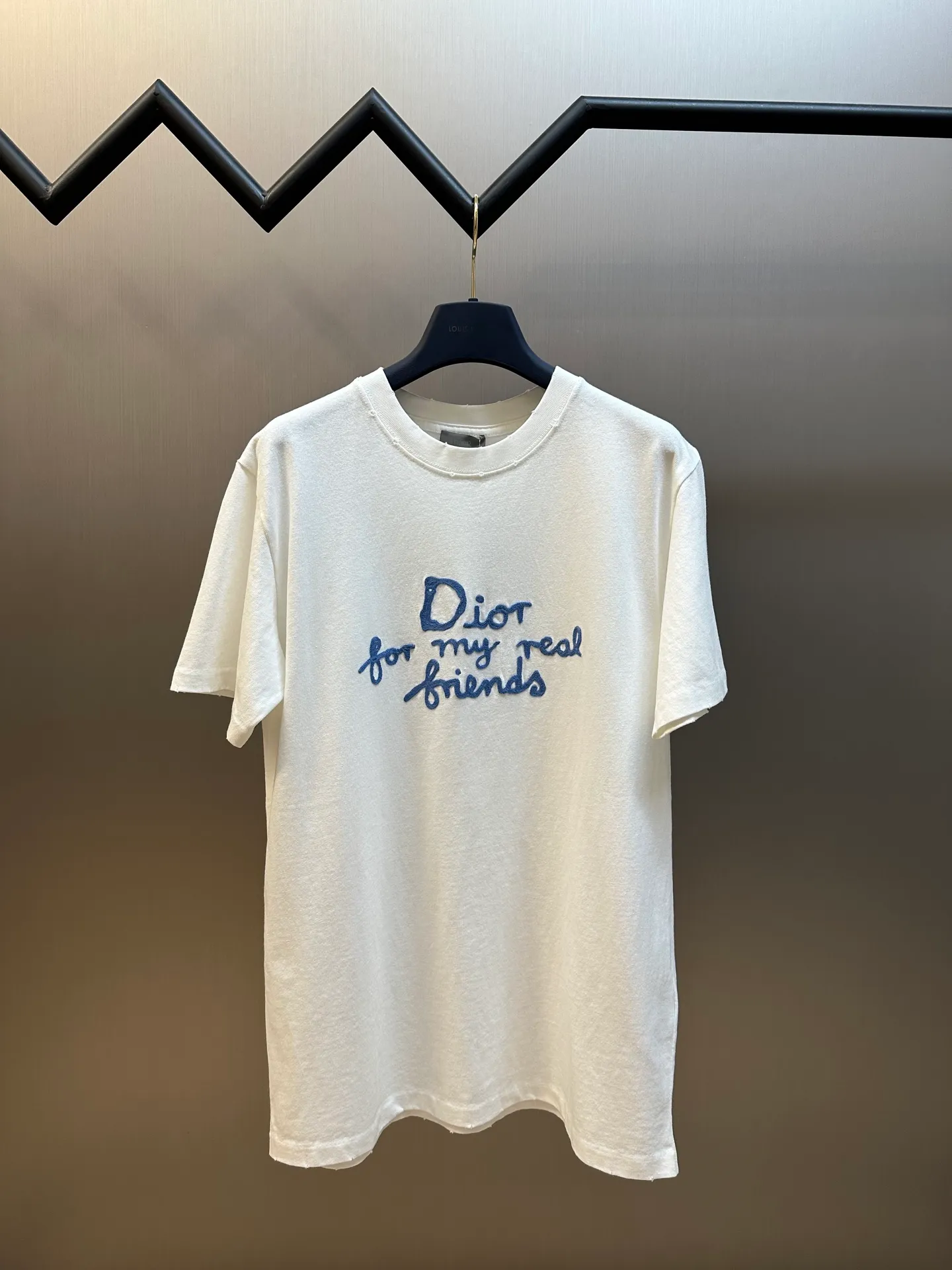 🅿️280 Dior Friends letter embroidered round neck short sleeves are made of pure cotton 12S fine cotton plain weave. The fabric is interwoven with plain weave. The yarns have many buckling points, which makes the fabric have good fastness and wear resistance. The density is moderate, the fabric is thin, flat and stiff. It has good breathability, is softer, more delicate, and has better gloss.  The joint series logo is chain embroidery. Chain embroidery is named because the visual effect of the embroidery is like a chain. The shape is like the links on the chain. It is commonly known as chain embroidery and also called chain eye embroidery. Follow the chain stitch stitch method and embroider from right to left. Maintain the tension of the embroidery thread and the uniformity of the stitches to ensure the three-dimensionality and exquisiteness of the embroidery. It combines the stitching method of chain embroidery with the material of fine wool to create embroidery with chain-like texture and three-dimensional effect.  The whole piece is designed with washed holes and irregular openings all over the body. The simple garments have a rebellious and destructive design. The stone grinding washing process locates the holes, and the ready-to-wear products use the stone grinding machine laser positioning to manually destroy the wear effect. Every wear and tear is made by hand, so that the natural wear and tear of the fabric achieves the most harmonious visual effect. After being washed by stone grinding, it can show a rich retro atmosphere.  The standard round neck and short-sleeved version has a rounded arc neckline, which is suitable for various face shapes and body shapes; the sleeve length is moderate and ends just above the elbow, showing a smart and neat image. The slim fit can show off the wearer's body curves without sacrificing comfort. The collar, cuffs, hem and other parts are all sewn with fine double-needle stitching.  size：xs s m l