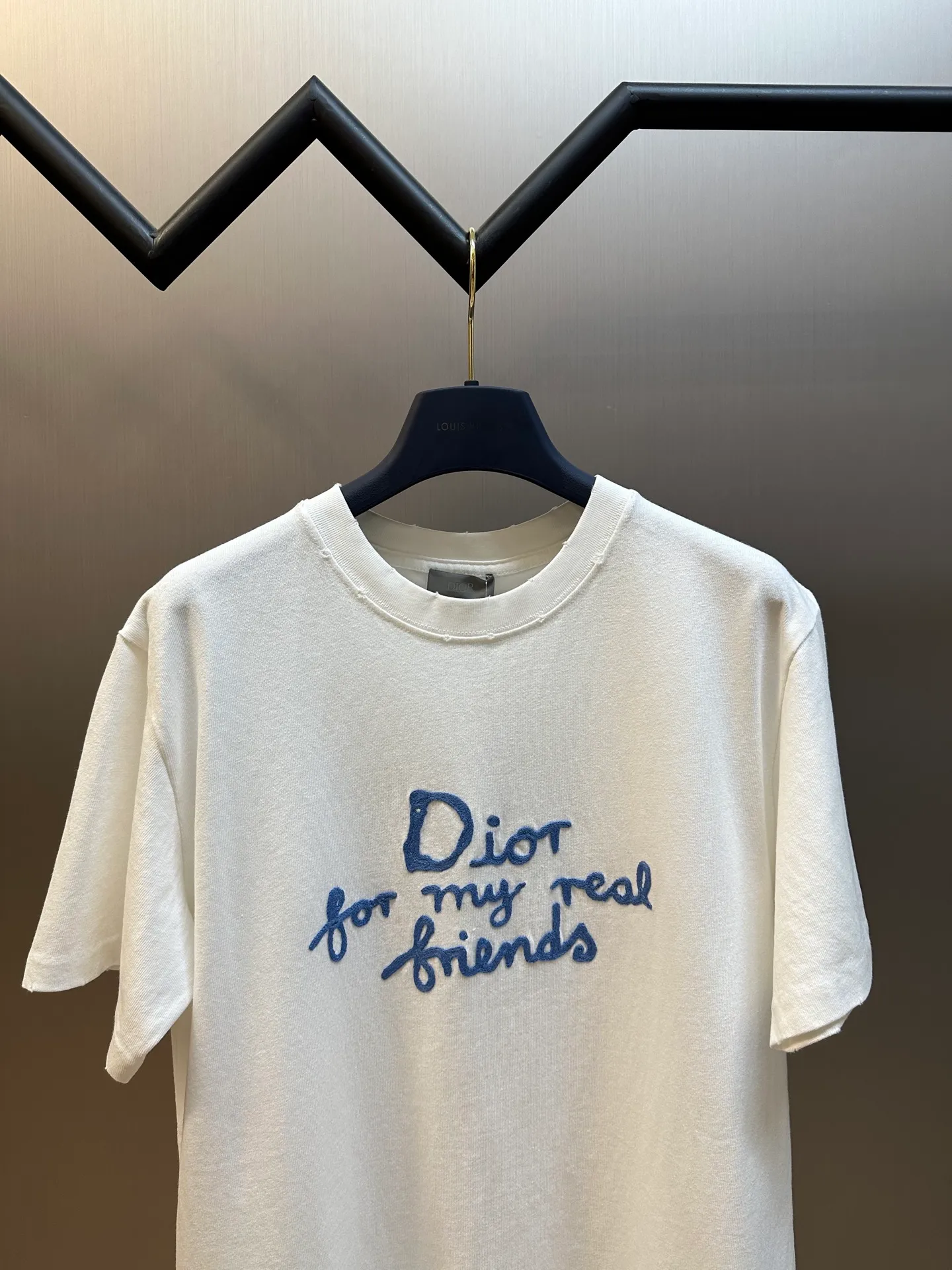 🅿️280 Dior Friends letter embroidered round neck short sleeves are made of pure cotton 12S fine cotton plain weave. The fabric is interwoven with plain weave. The yarns have many buckling points, which makes the fabric have good fastness and wear resistance. The density is moderate, the fabric is thin, flat and stiff. It has good breathability, is softer, more delicate, and has better gloss.  The joint series logo is chain embroidery. Chain embroidery is named because the visual effect of the embroidery is like a chain. The shape is like the links on the chain. It is commonly known as chain embroidery and also called chain eye embroidery. Follow the chain stitch stitch method and embroider from right to left. Maintain the tension of the embroidery thread and the uniformity of the stitches to ensure the three-dimensionality and exquisiteness of the embroidery. It combines the stitching method of chain embroidery with the material of fine wool to create embroidery with chain-like texture and three-dimensional effect.  The whole piece is designed with washed holes and irregular openings all over the body. The simple garments have a rebellious and destructive design. The stone grinding washing process locates the holes, and the ready-to-wear products use the stone grinding machine laser positioning to manually destroy the wear effect. Every wear and tear is made by hand, so that the natural wear and tear of the fabric achieves the most harmonious visual effect. After being washed by stone grinding, it can show a rich retro atmosphere.  The standard round neck and short-sleeved version has a rounded arc neckline, which is suitable for various face shapes and body shapes; the sleeve length is moderate and ends just above the elbow, showing a smart and neat image. The slim fit can show off the wearer's body curves without sacrificing comfort. The collar, cuffs, hem and other parts are all sewn with fine double-needle stitching.  size：xs s m l